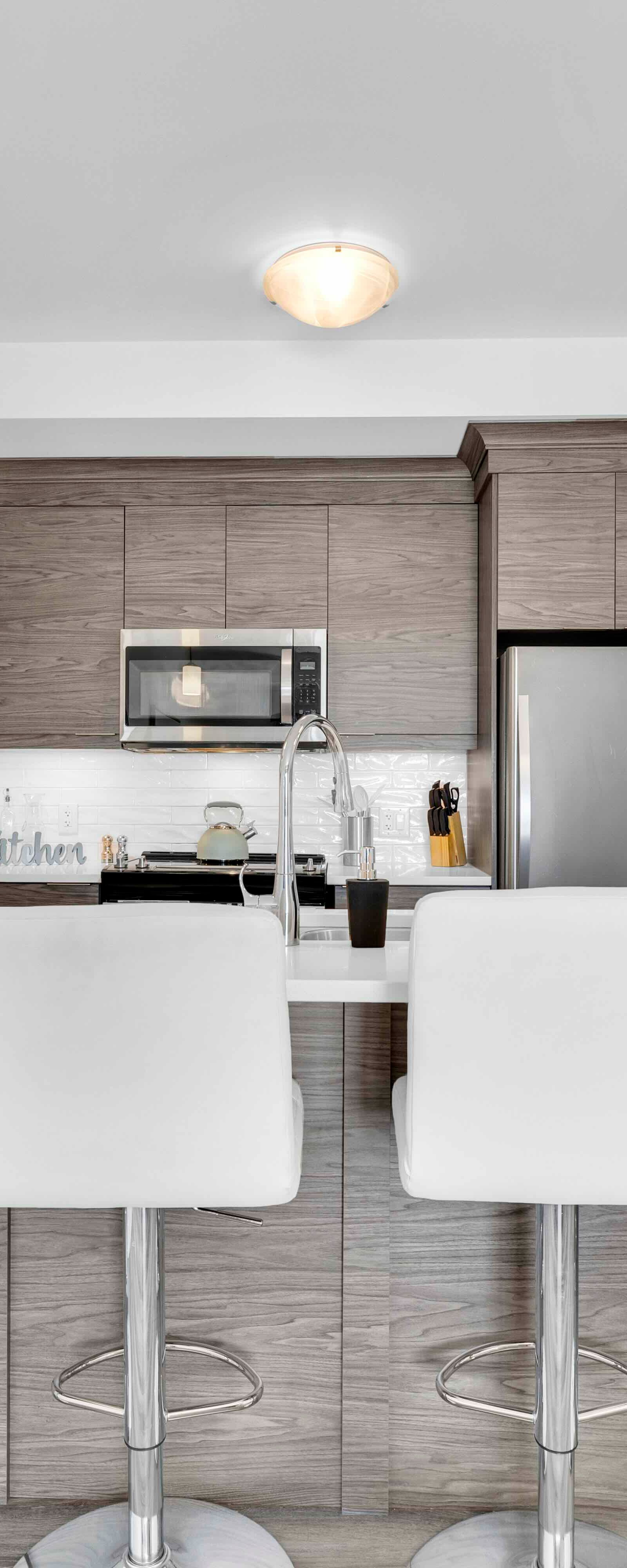 Kitchen island from front showing quartz countertop, sink, and wood-grain cabinetry