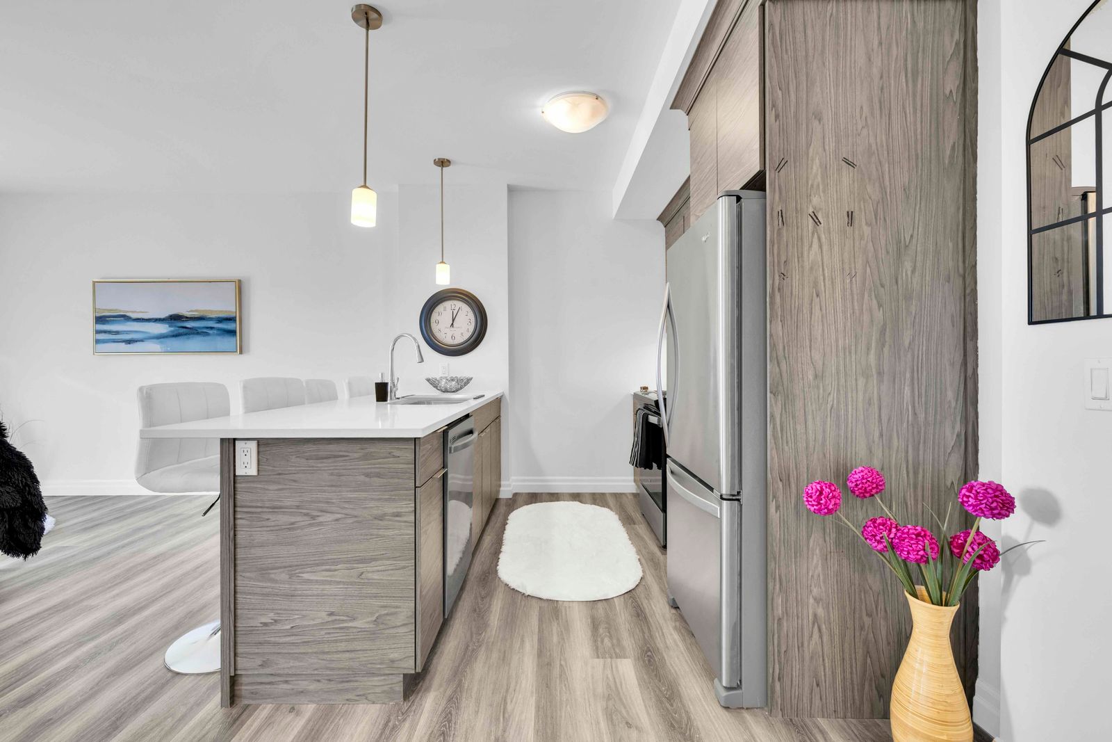 Kitchen island with bar stools, refrigerator, and artwork