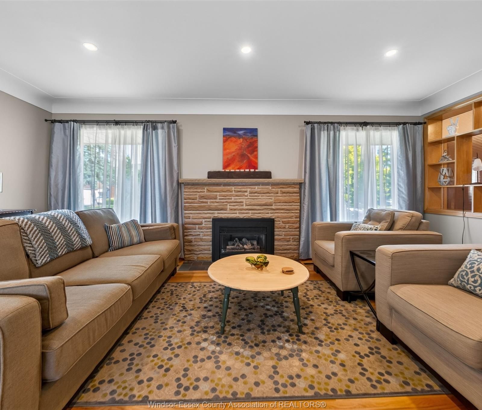 Living room with stone fireplace, seating and built-in shelving