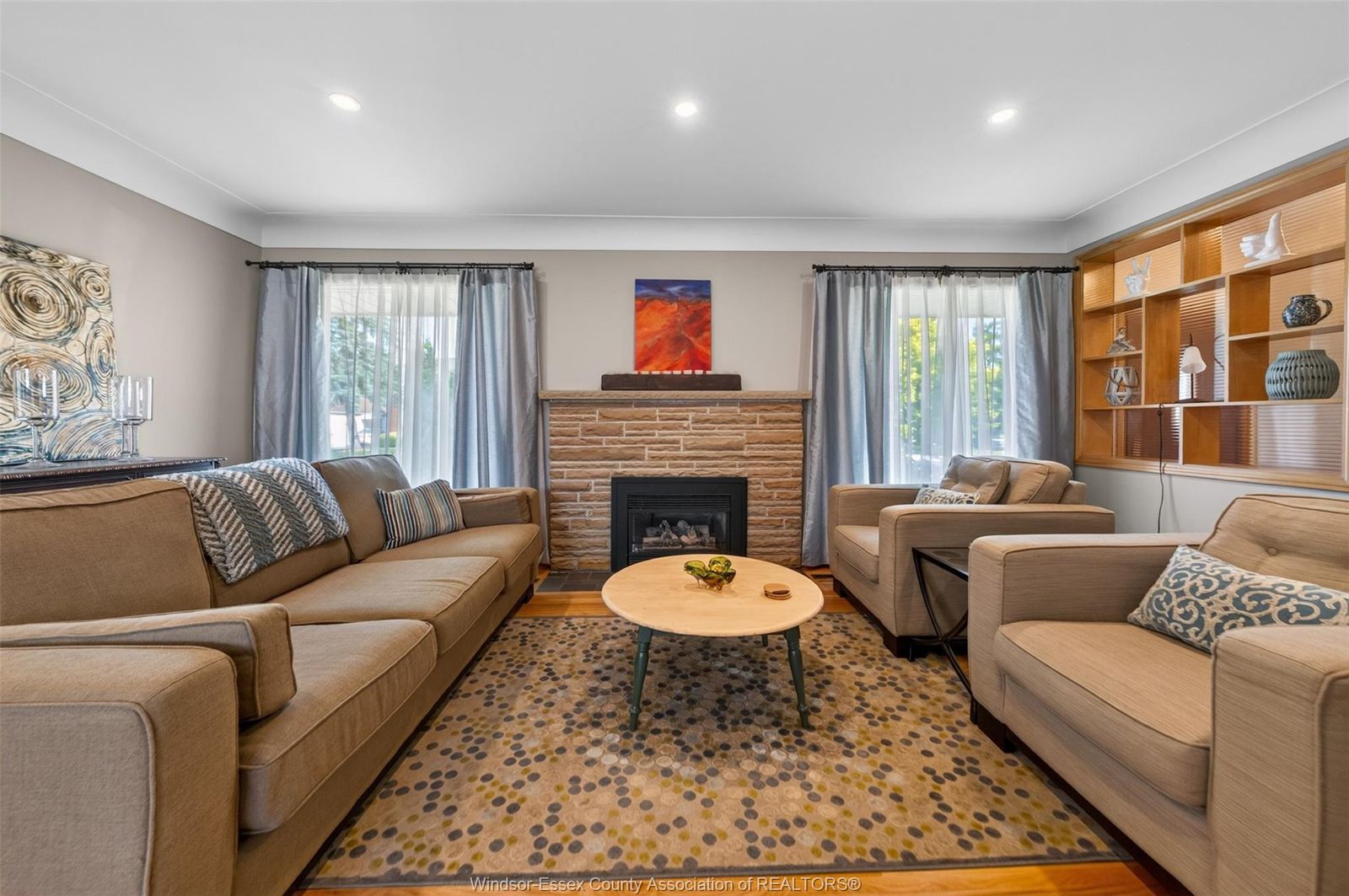 Living room with stone fireplace, seating and built-in shelving