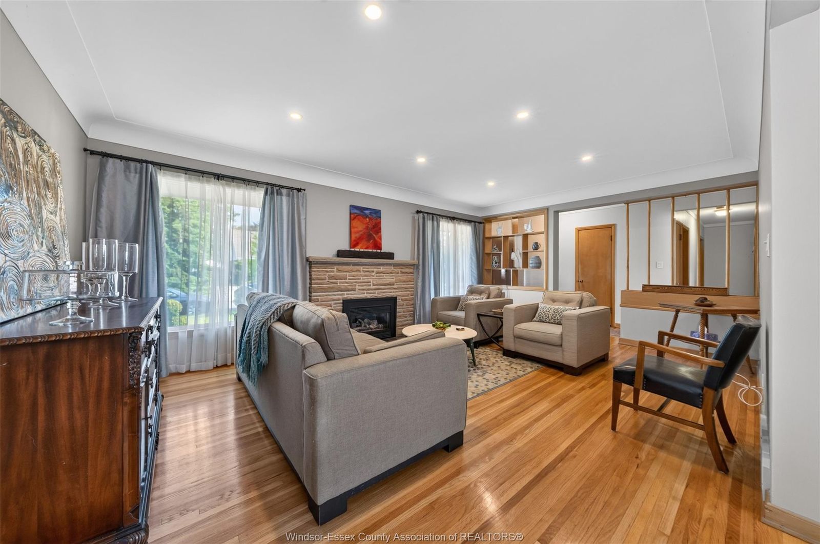 Bright living room showing the gas fireplace insert and gleaming hardwood floors