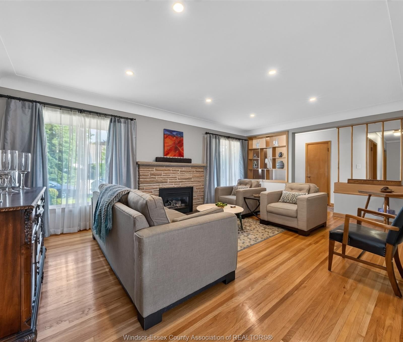 Bright living room showing the gas fireplace insert and gleaming hardwood floors
