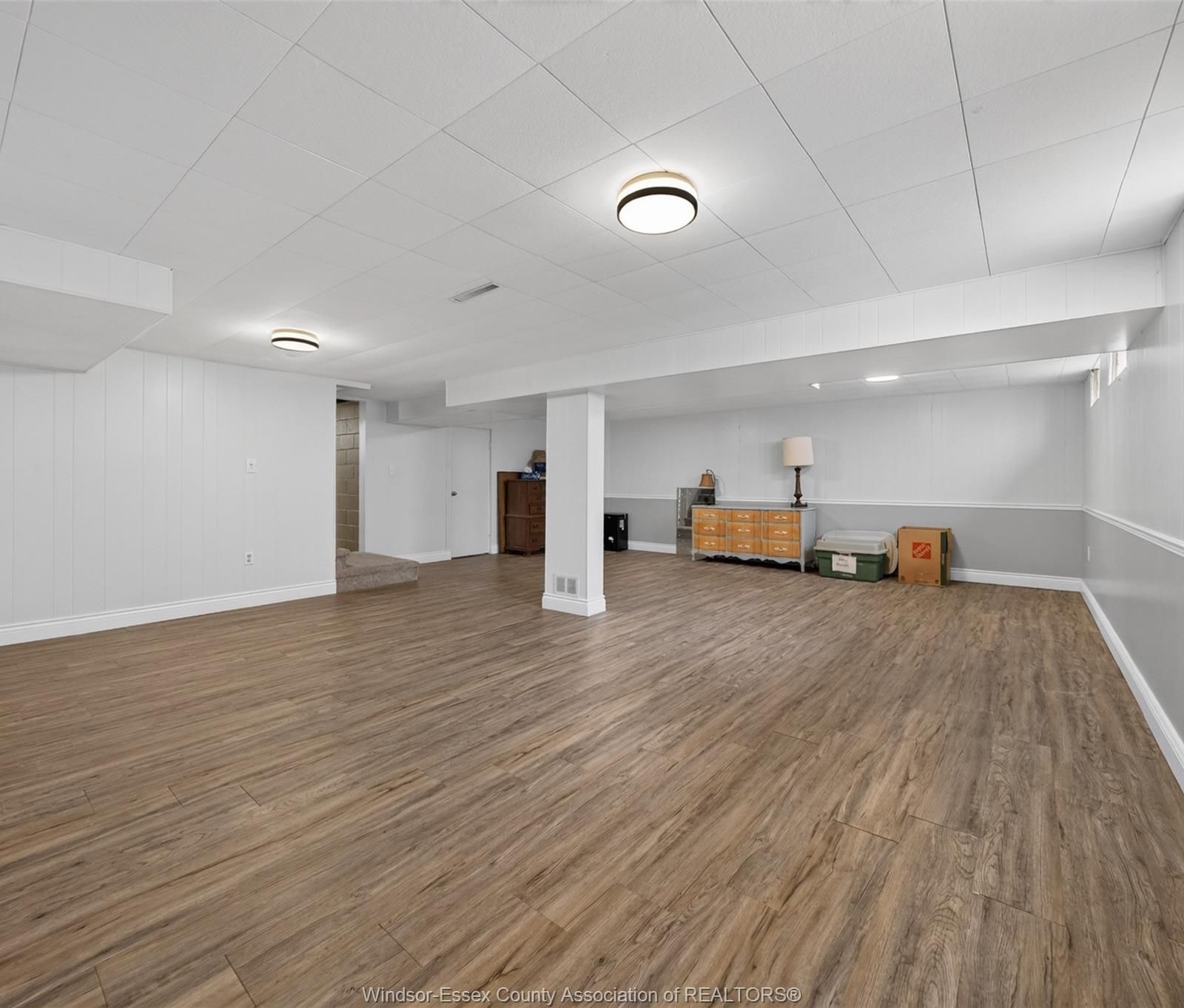Spacious finished basement with wood-look floors and multiple light fixtures