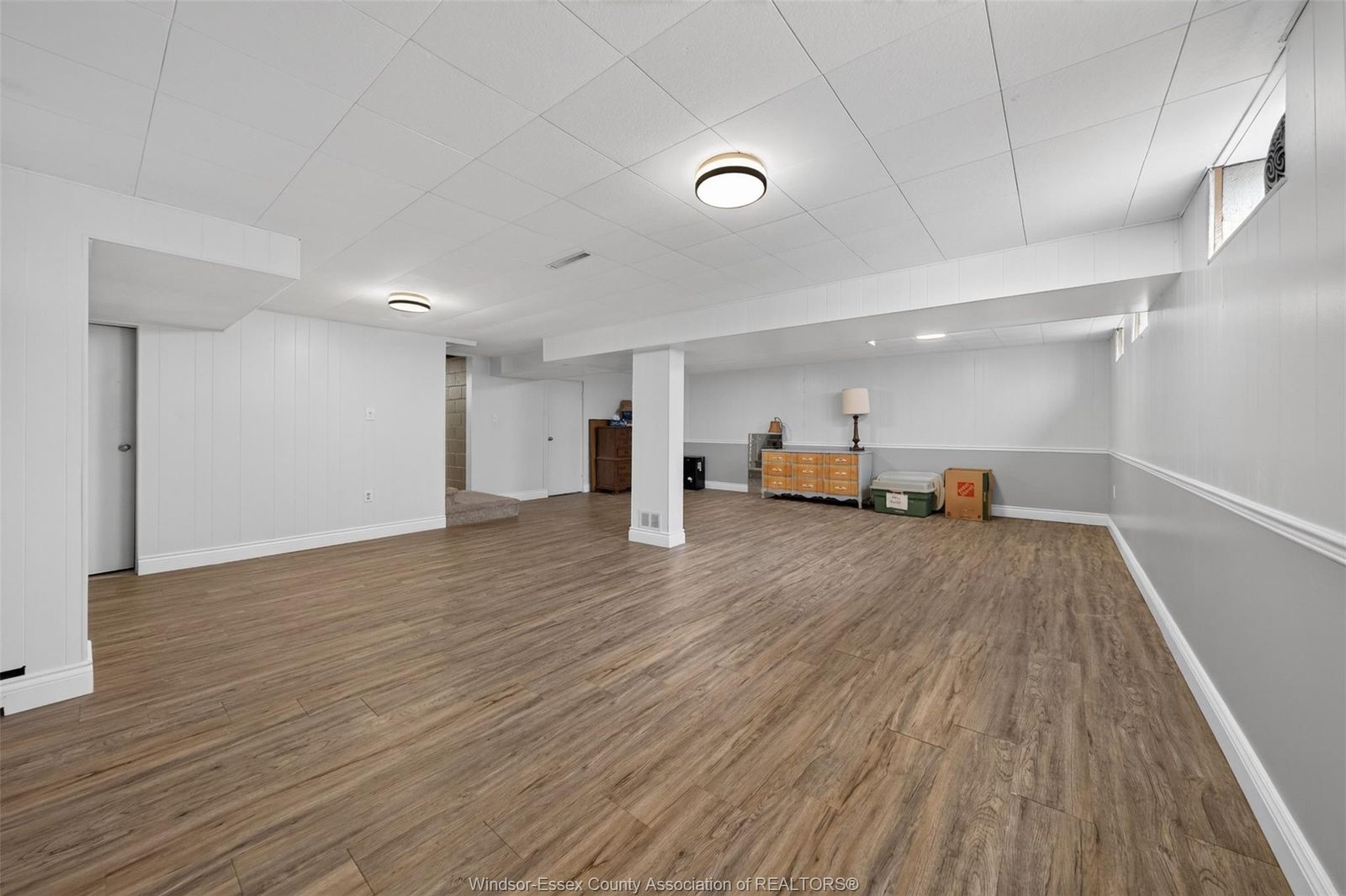 Spacious finished basement with wood-look floors and multiple light fixtures