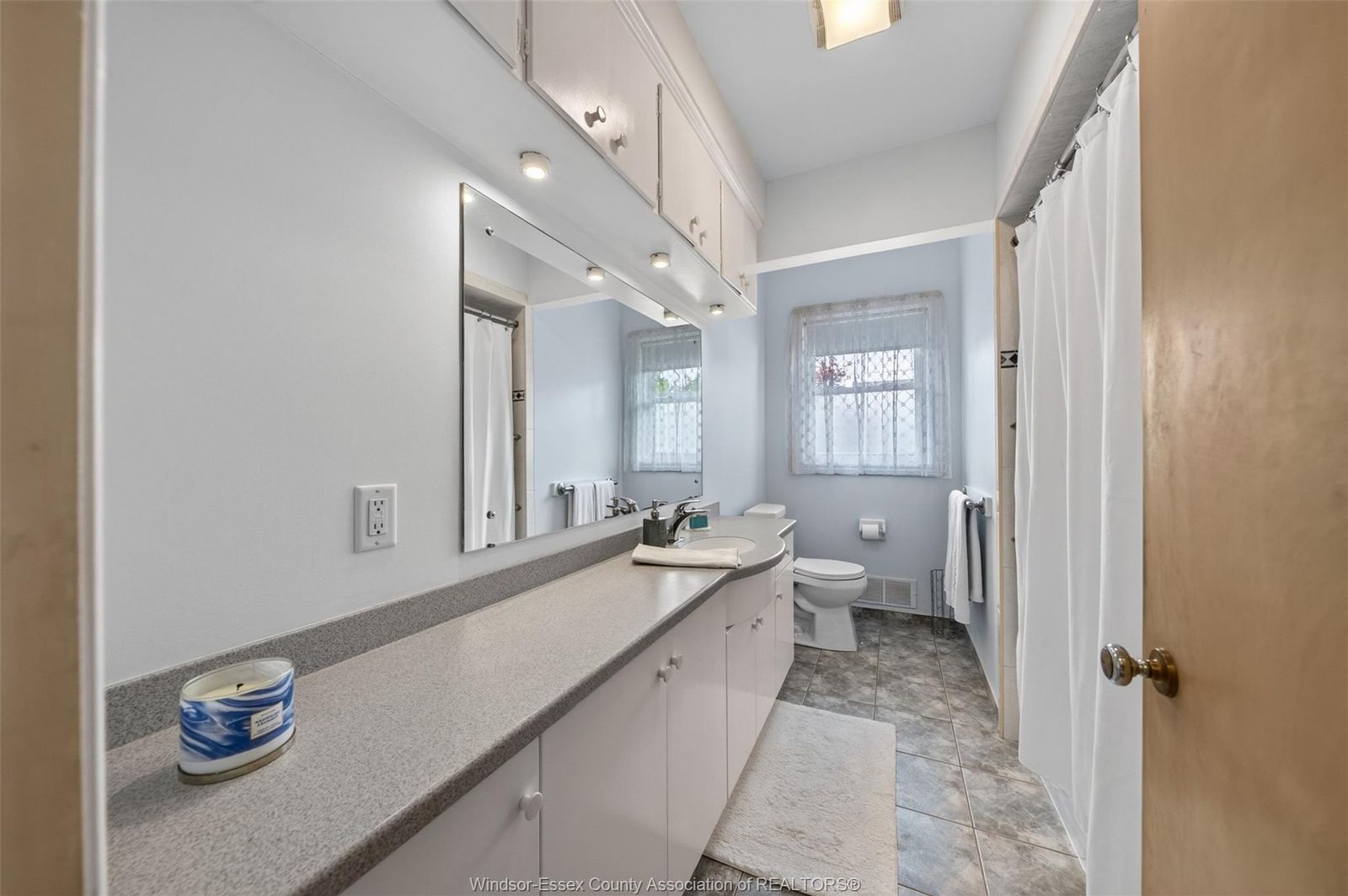 4-piece bathroom with long countertop, integrated sink, mirror and shower