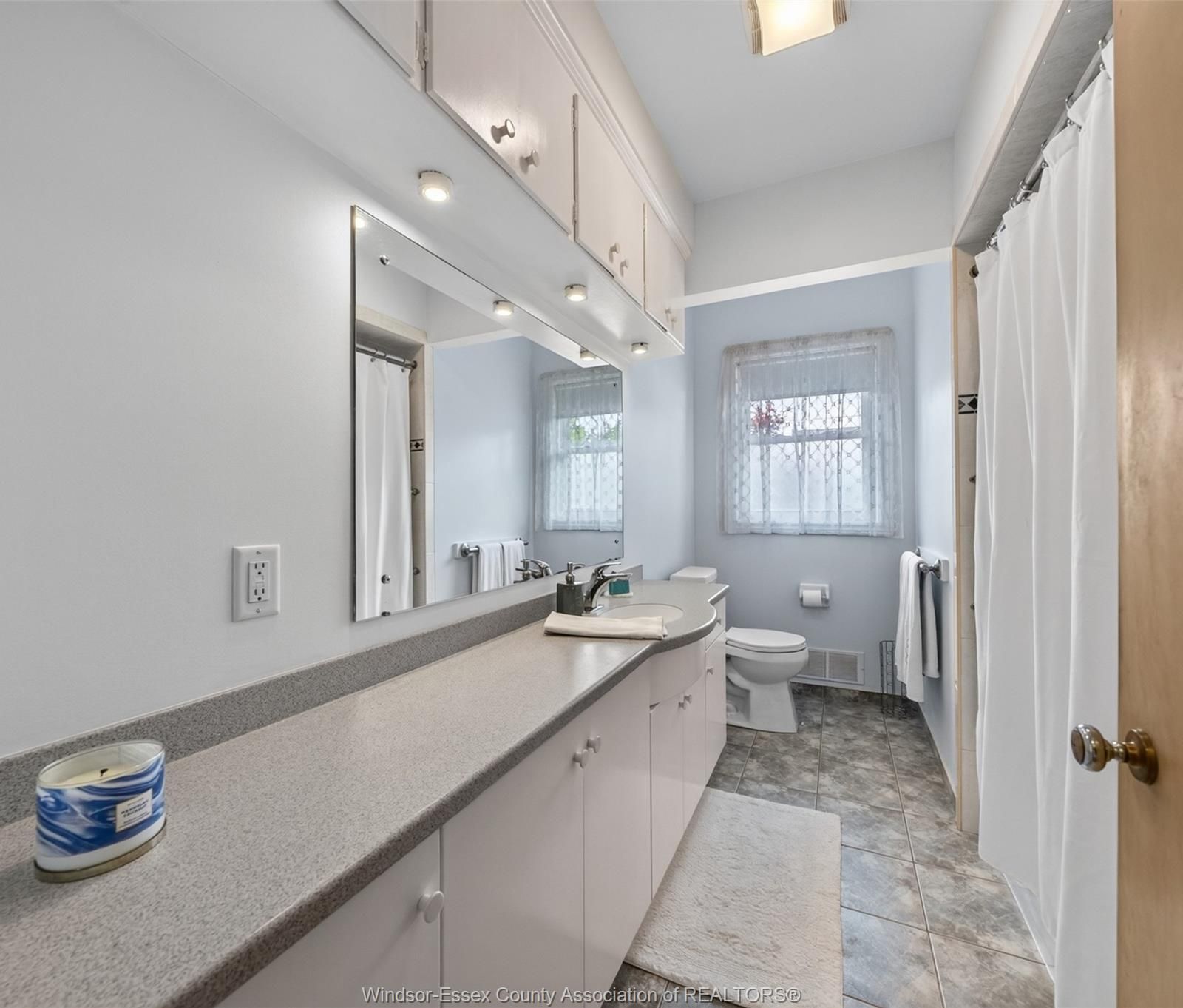 4-piece bathroom with long countertop, integrated sink, mirror and shower