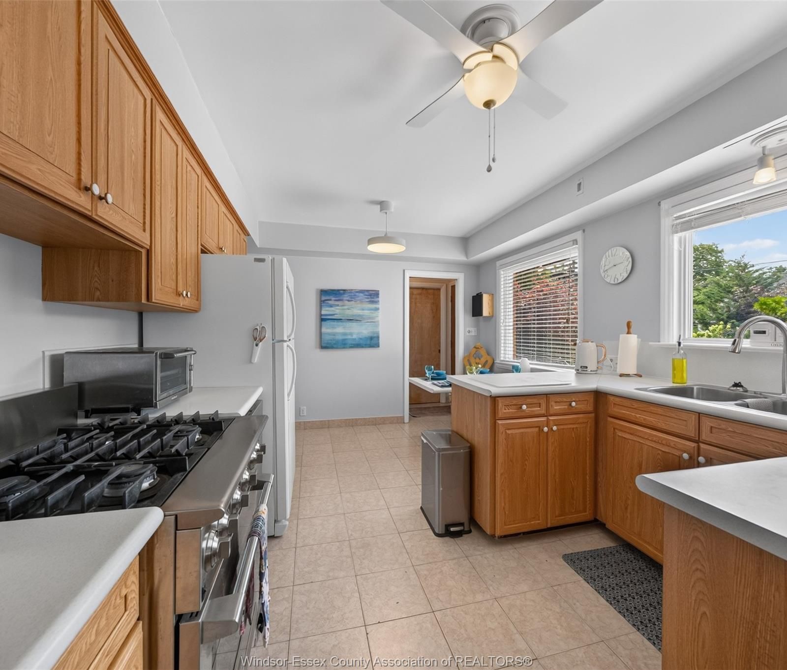 Kitchen with wood cabinetry, white countertops and gas stove