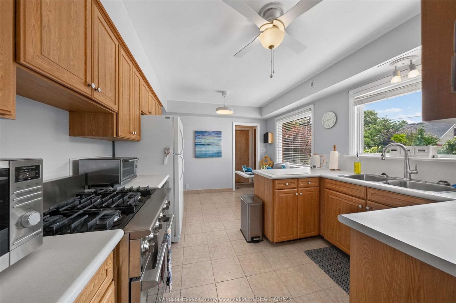 Kitchen with wood cabinetry, white countertops and gas stove