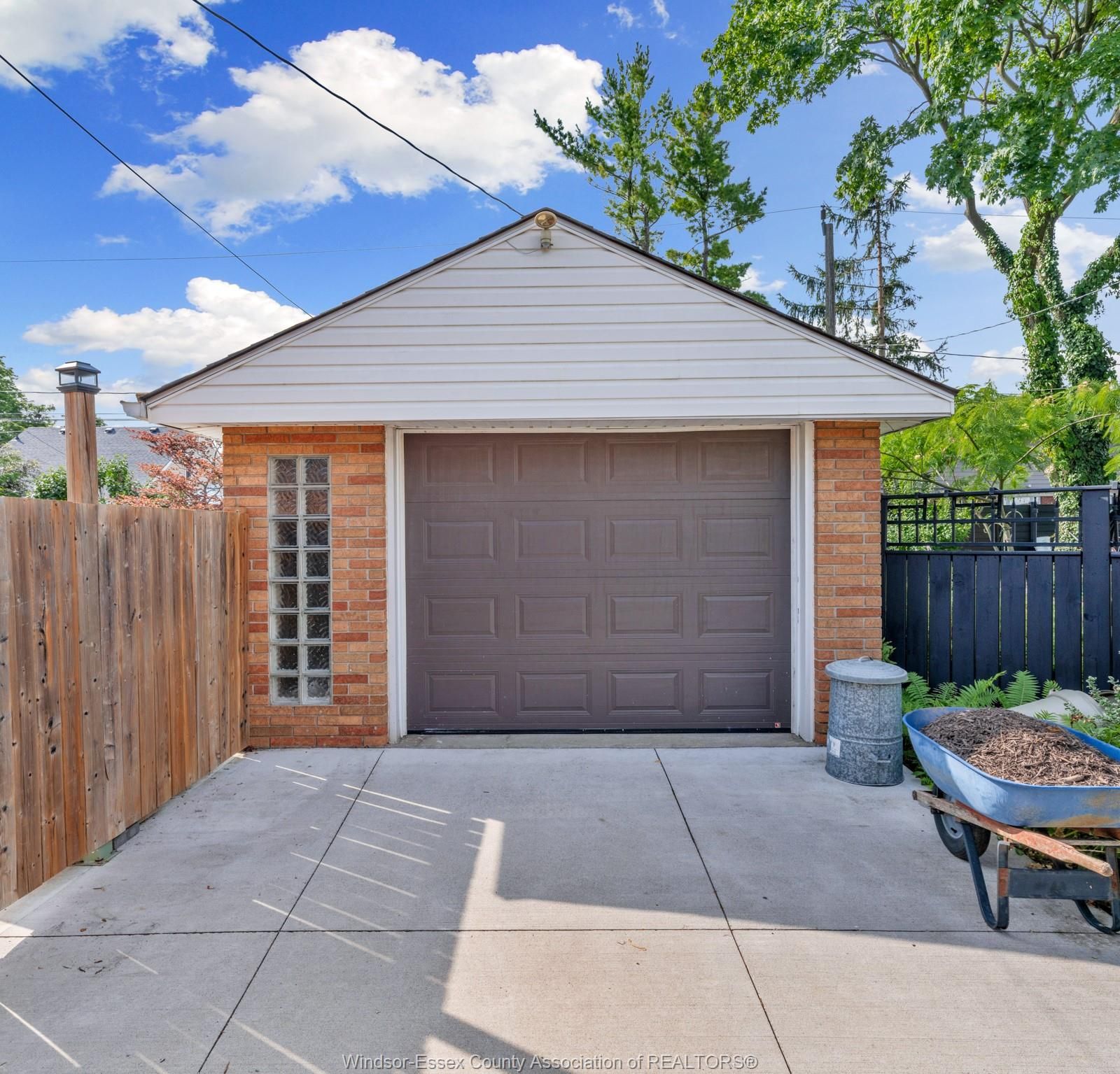 Detached brick garage with glass block window and concrete driveway