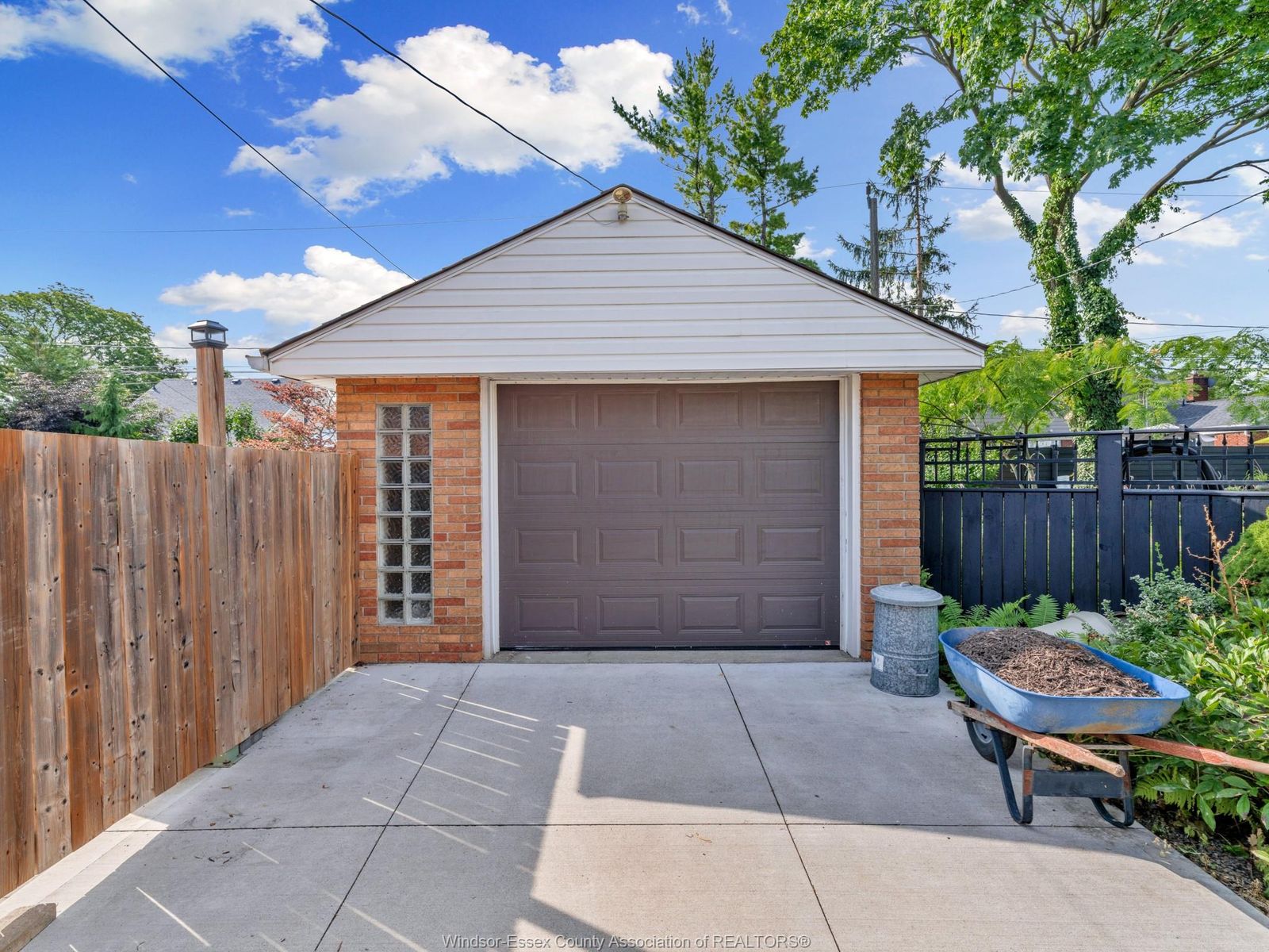 Detached brick garage with glass block window and concrete driveway