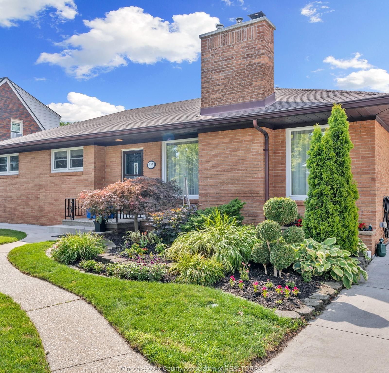 Corner view of the house with driveway, walkway and landscaped flower beds