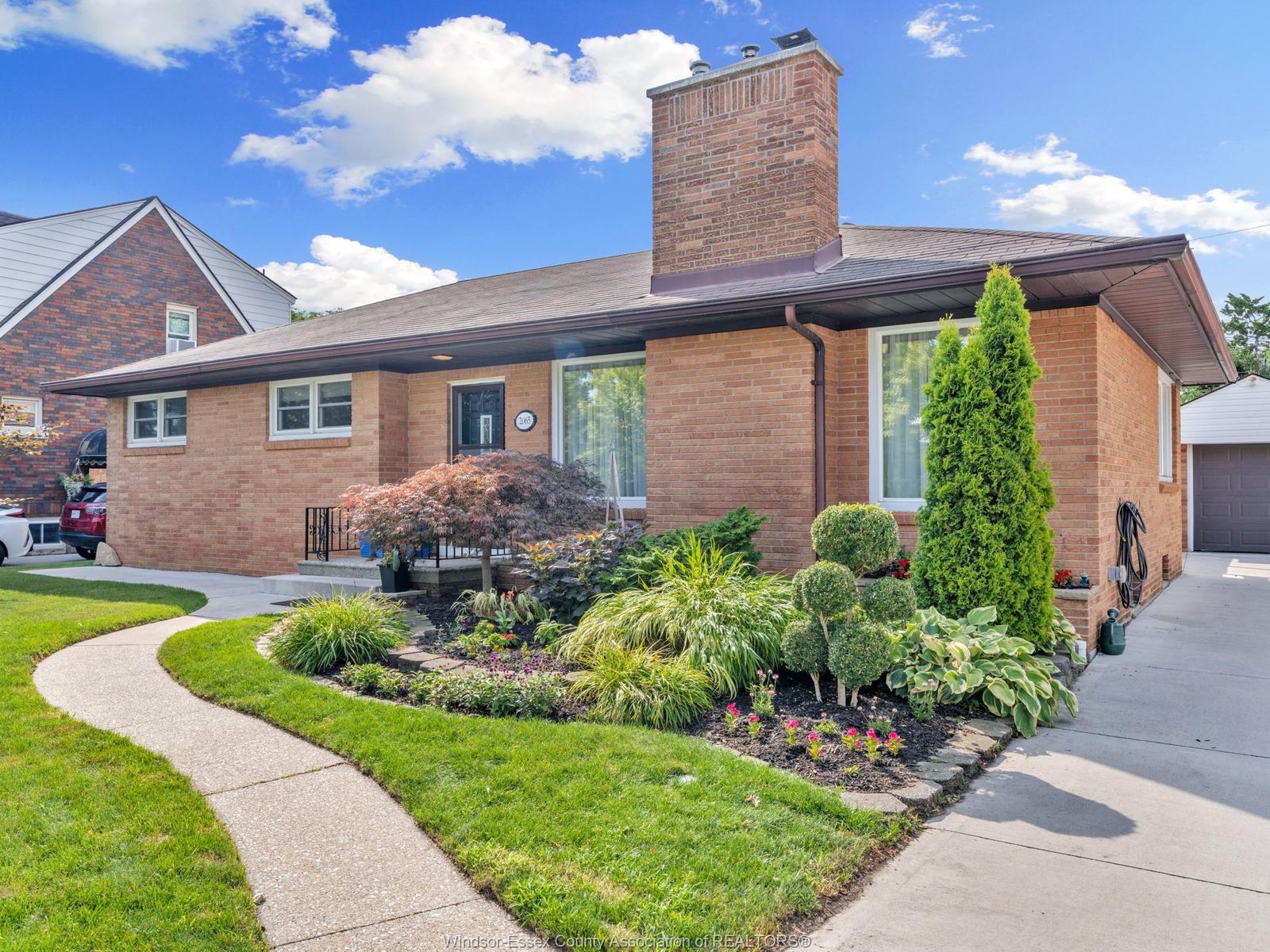 Corner view of the house with driveway, walkway and landscaped flower beds