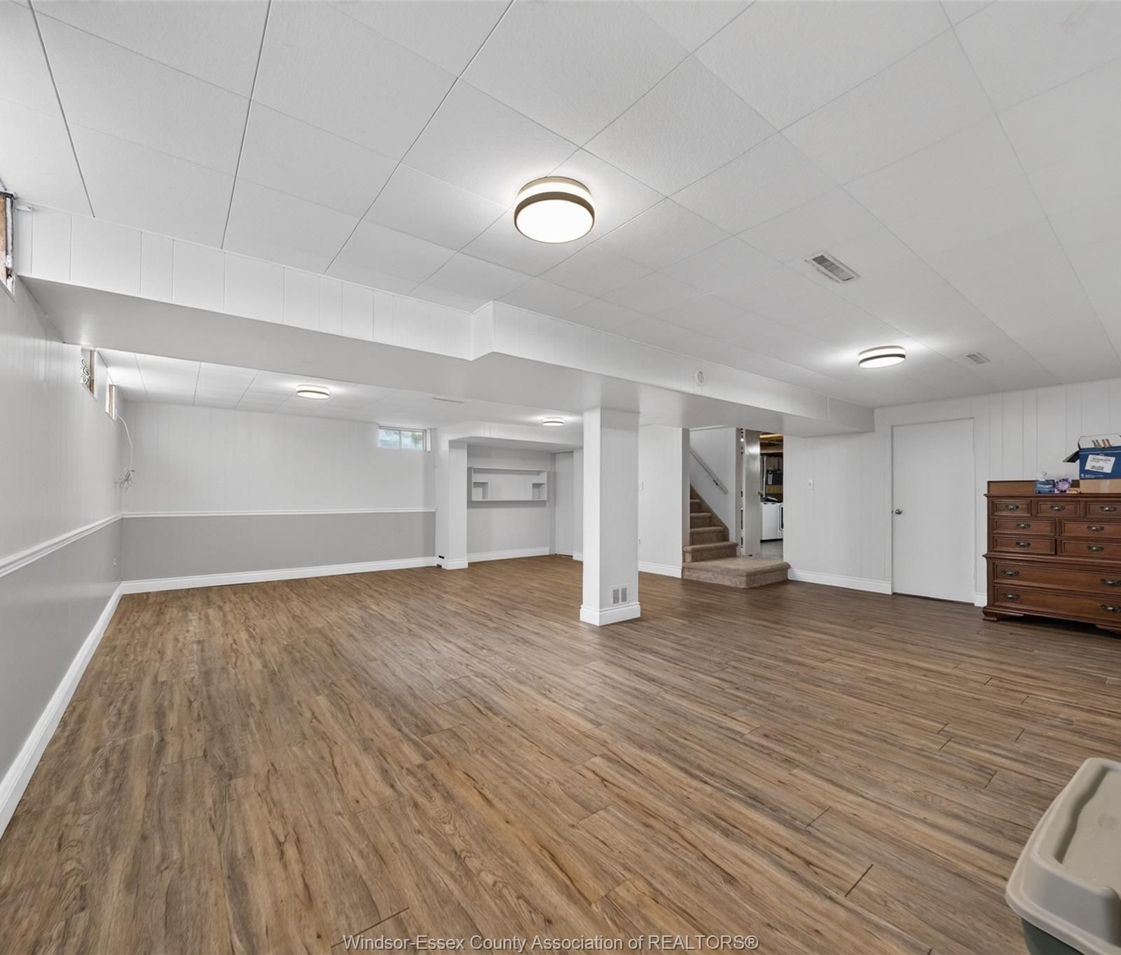 Finished basement room with wood-look flooring and white walls