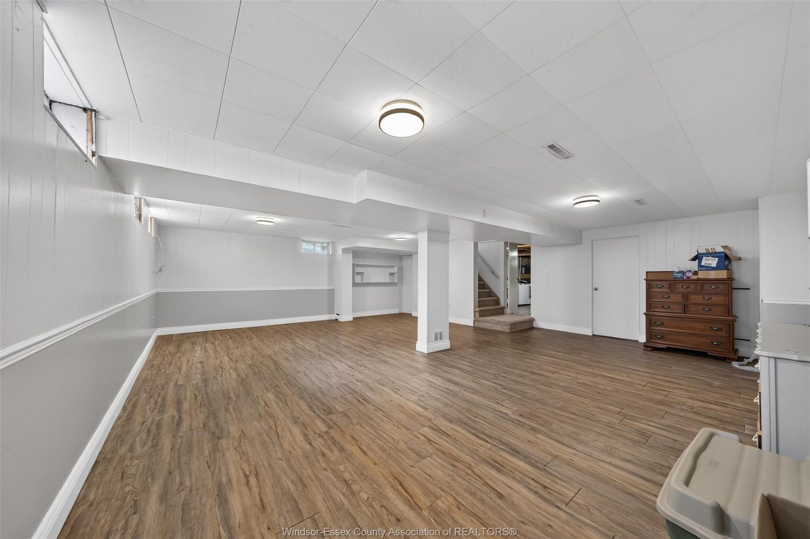 Finished basement room with wood-look flooring and white walls