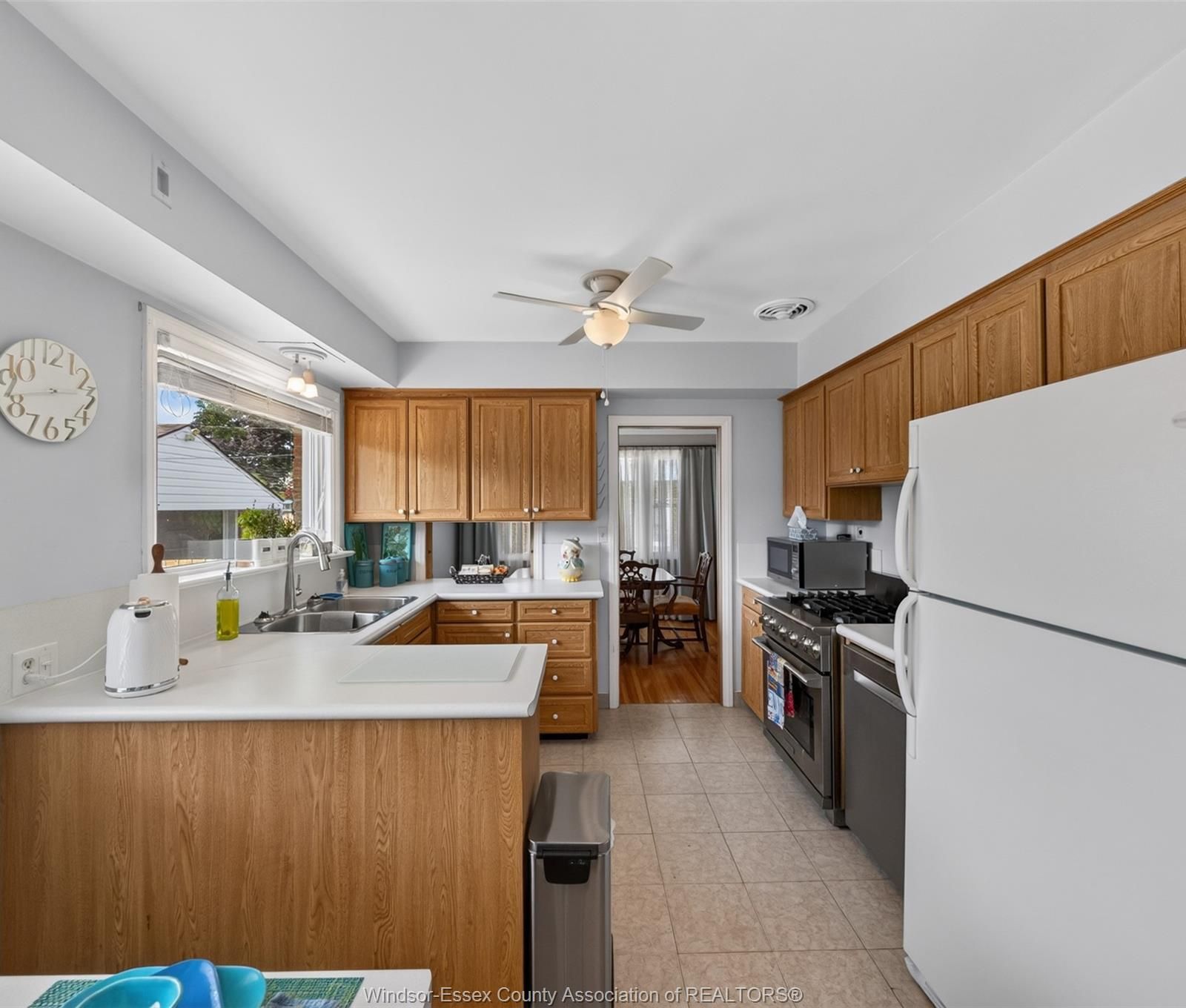 Kitchen sink and cabinetry with ceiling fan and window