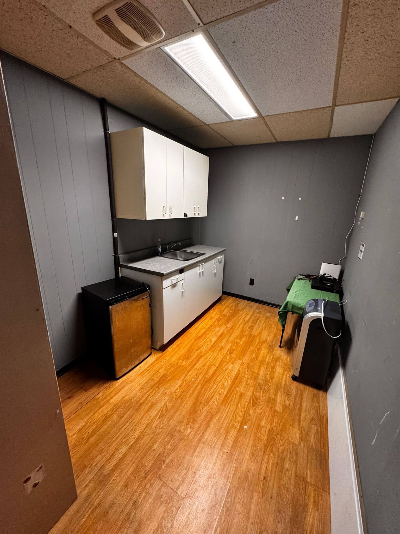 Utility kitchenette with sink, cabinetry, and compact fridge