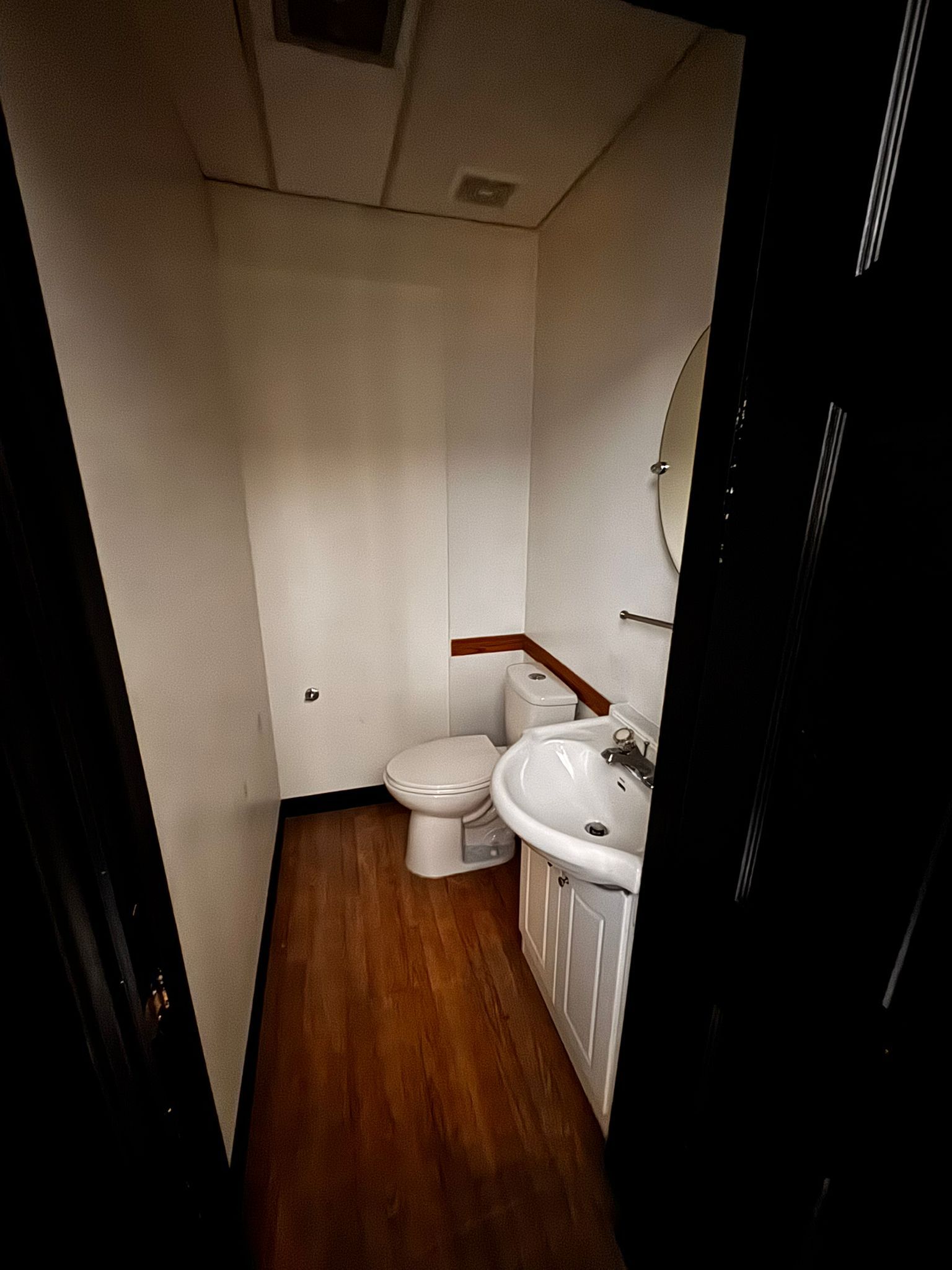 Private bathroom with toilet, sink, and round mirror