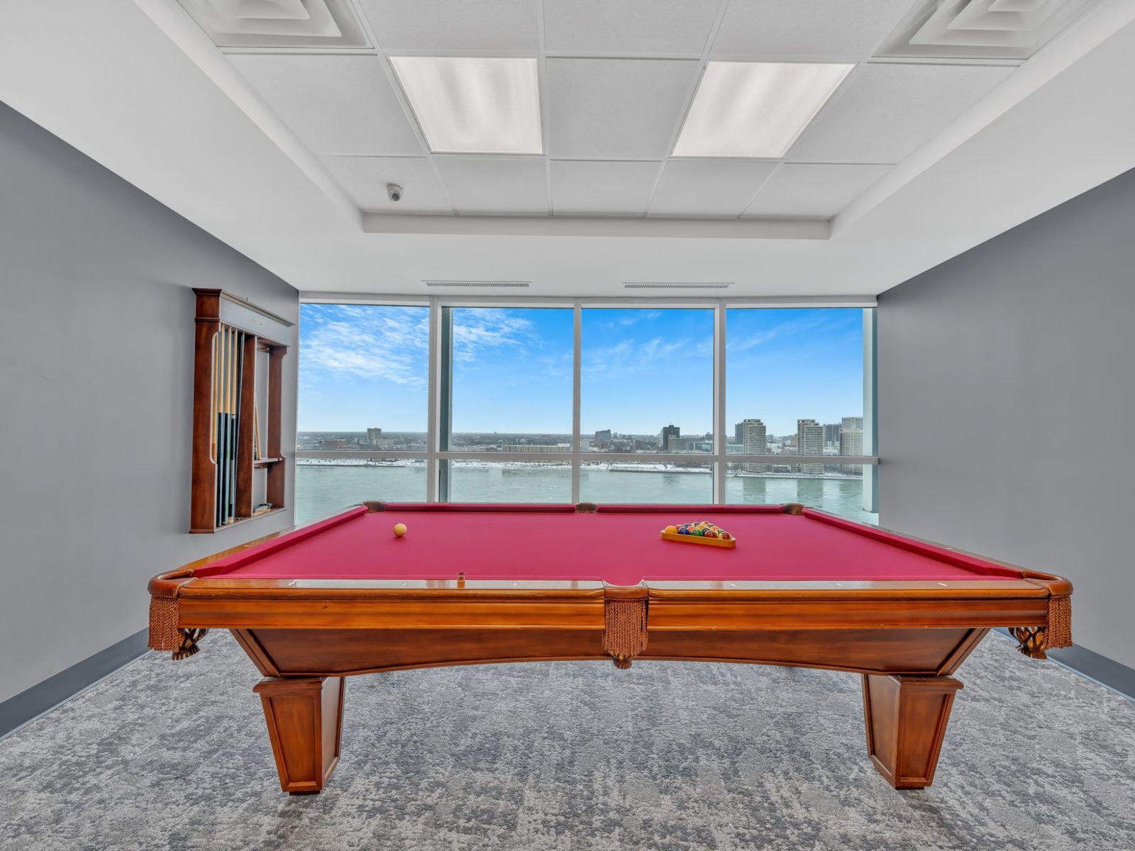 Pool table with floor-to-ceiling window and city water view