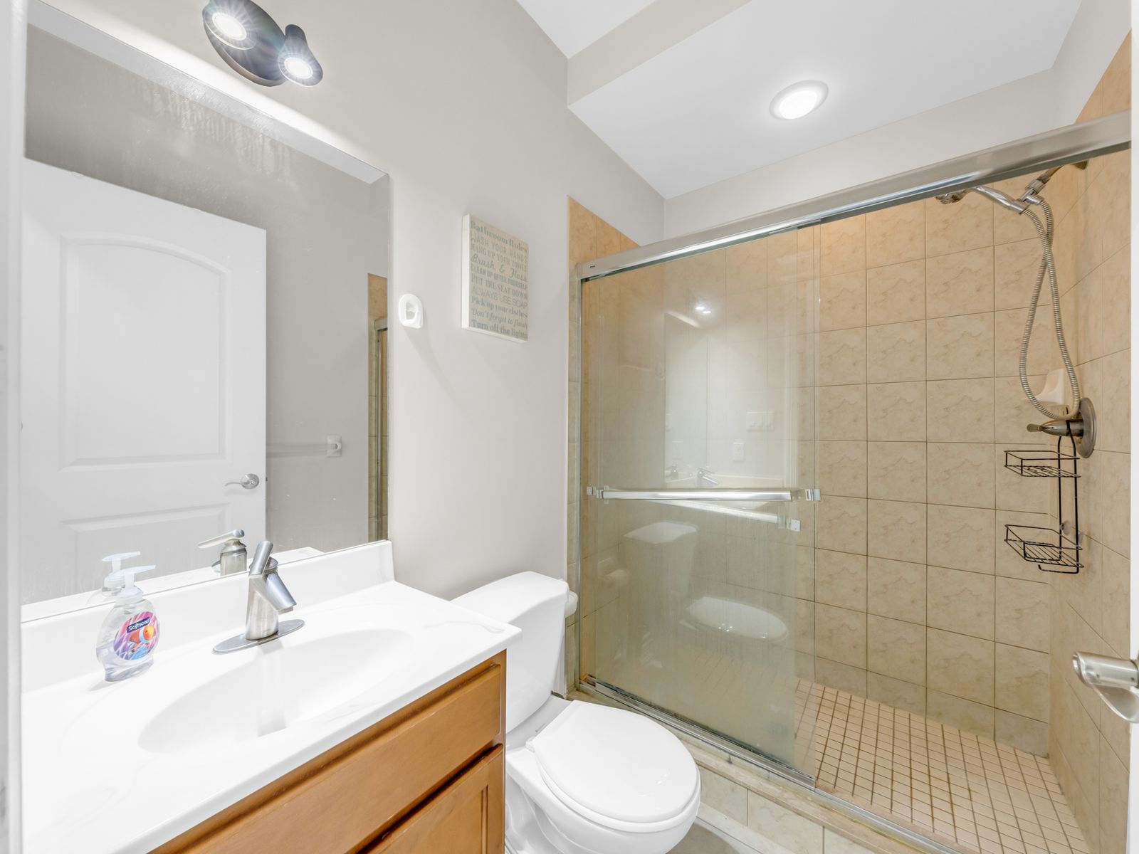 Bathroom with glass sliding shower door and tiled walls