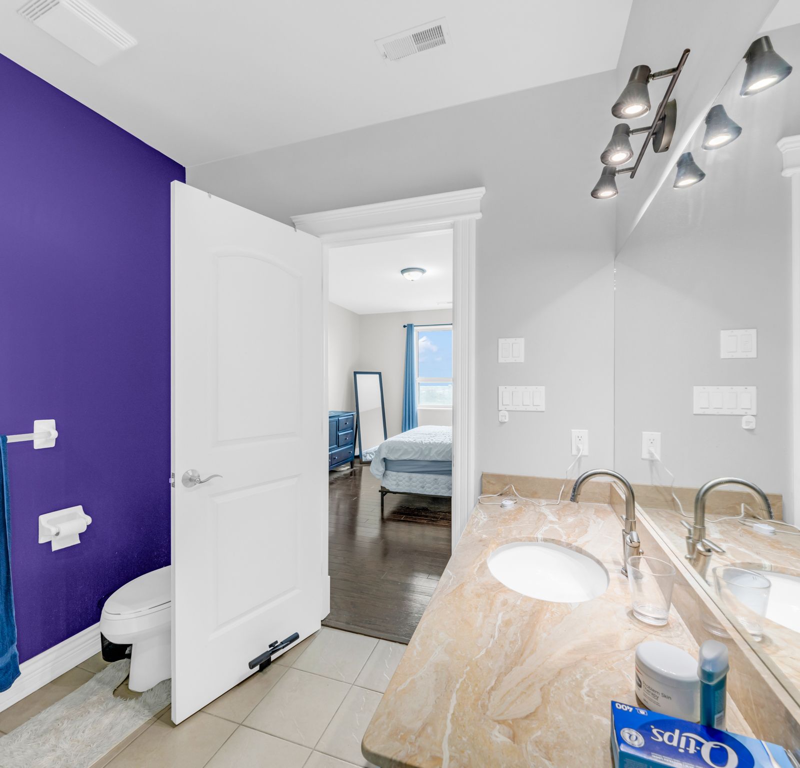 Second bathroom with purple accent wall and marble vanity