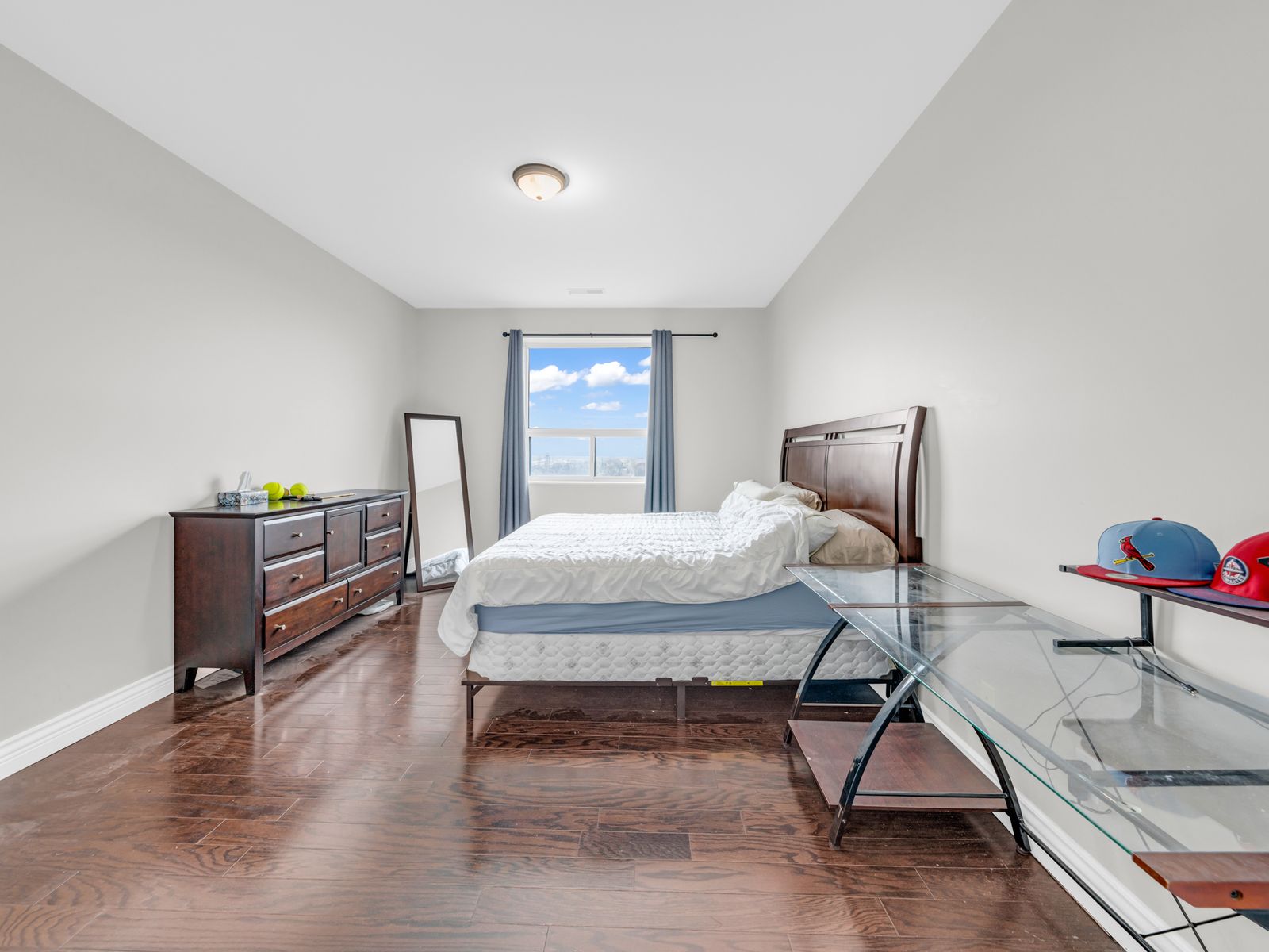 Primary bedroom with sky view window and hardwood floor