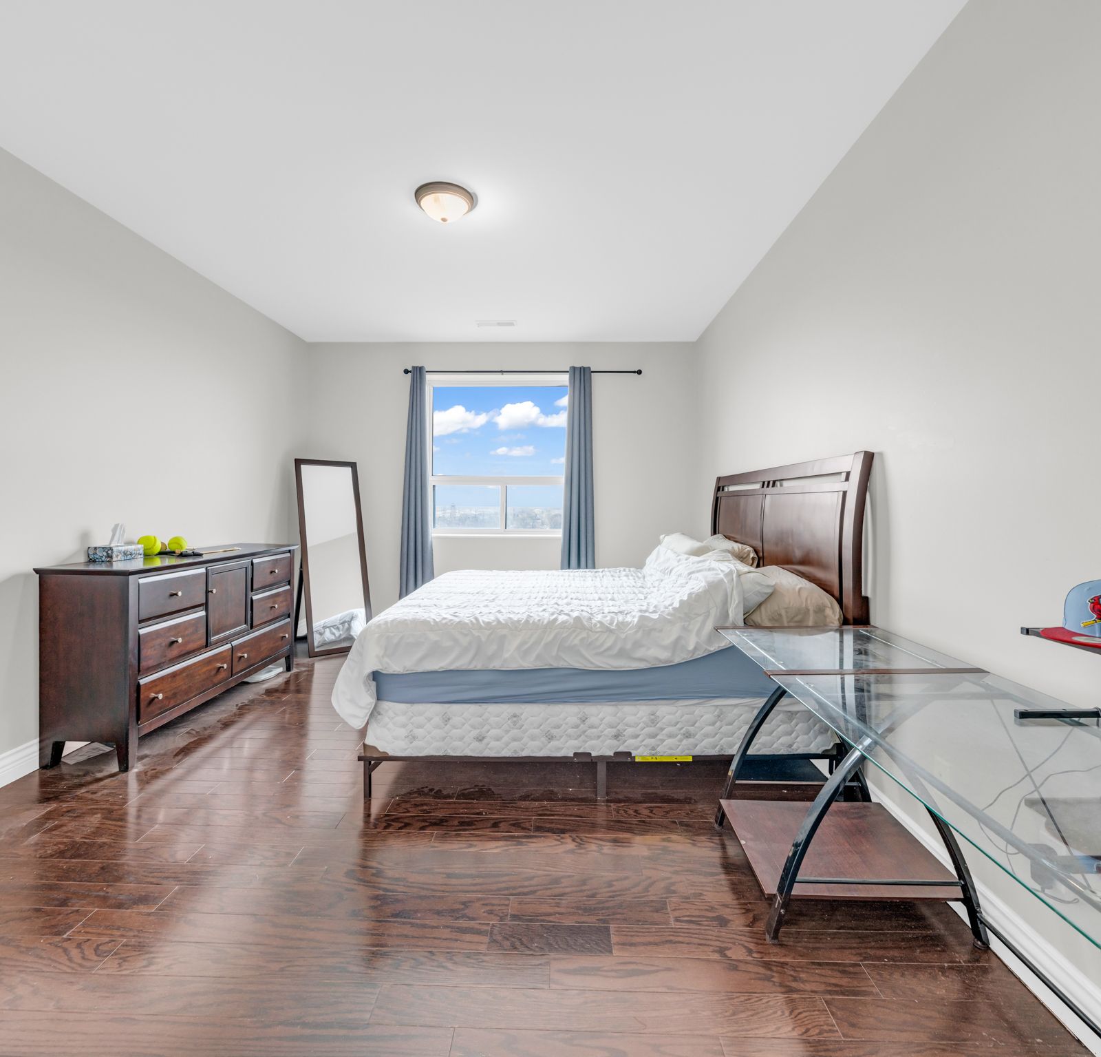 Primary bedroom with sky view window and hardwood floor