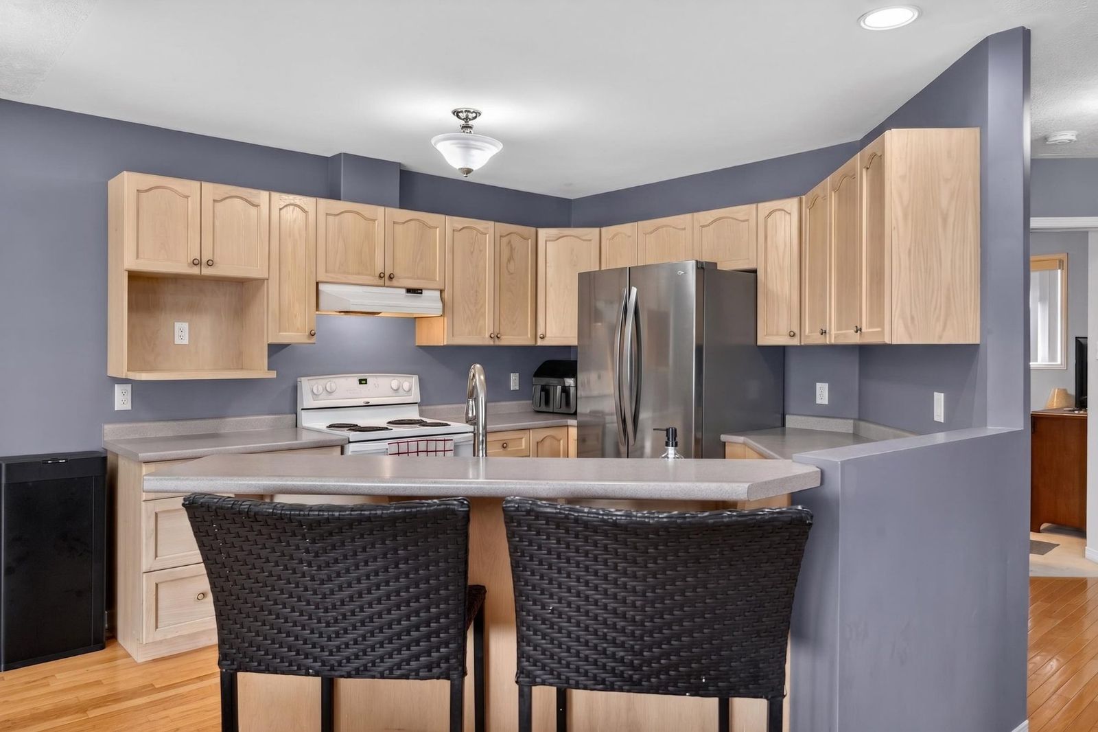 Kitchen view from breakfast bar side showing cabinetry and stove