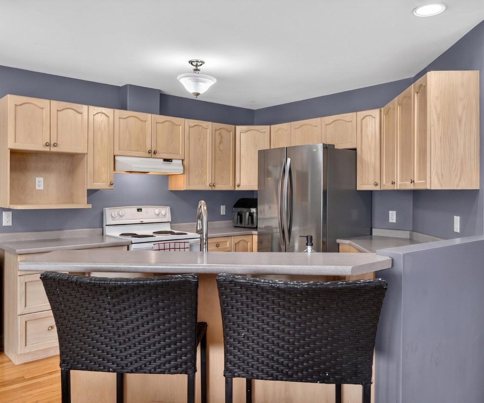 Kitchen view from breakfast bar side showing cabinetry and stove
