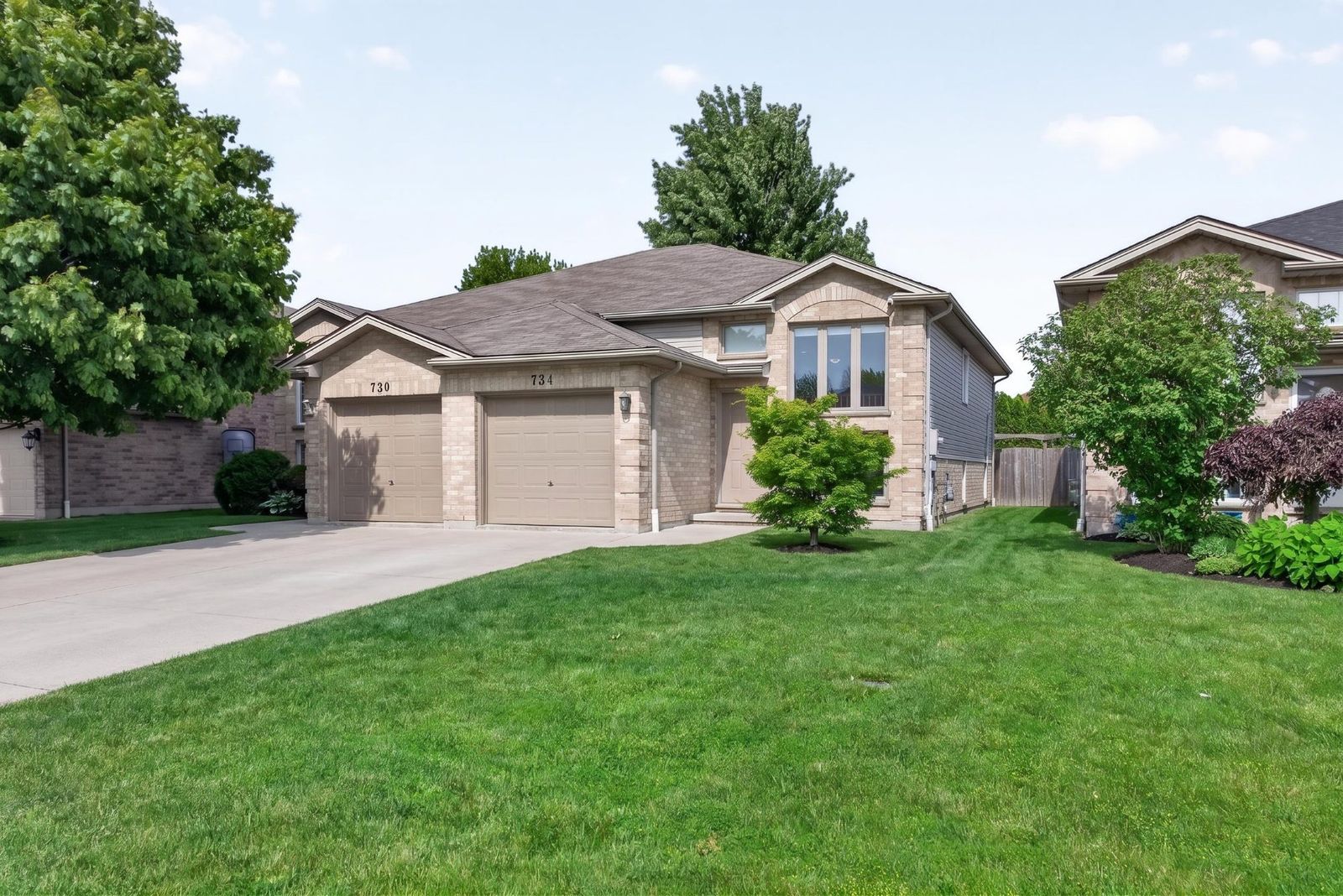 Wide front view of 734 Michael with green lawn and mature trees