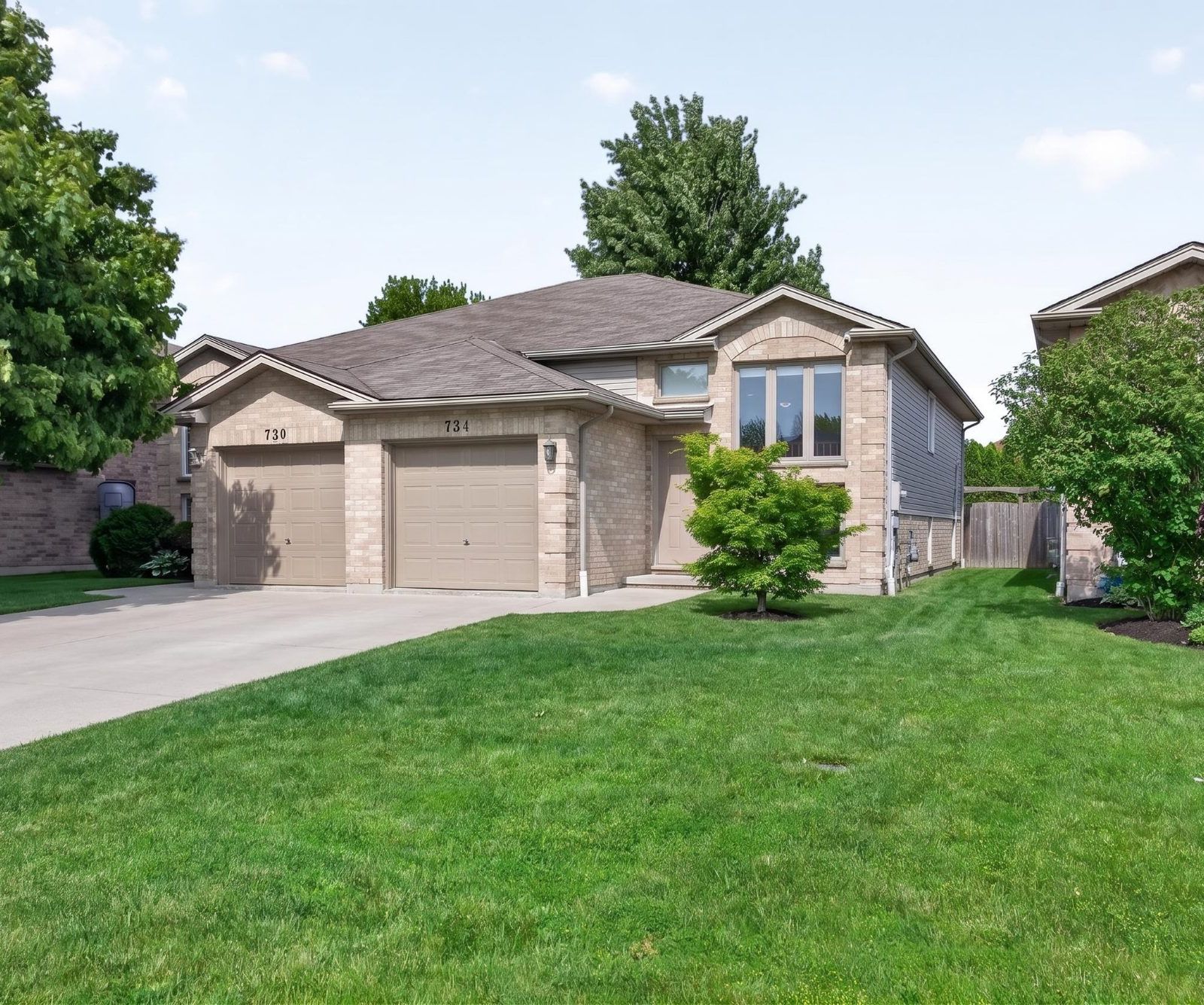 Wide front view of 734 Michael with green lawn and mature trees
