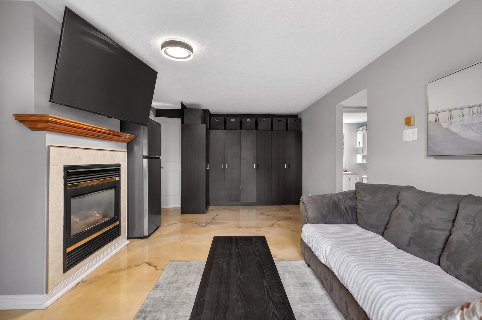 Lower level living room with gas fireplace, mounted TV, and storage cabinets
