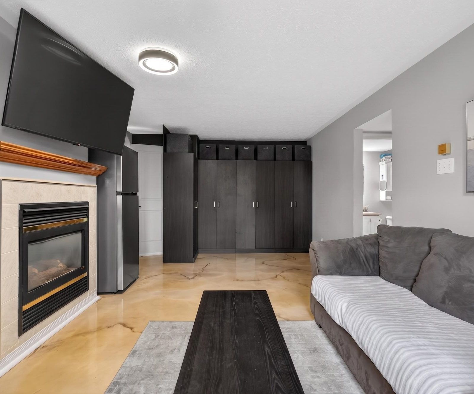 Lower level living room with gas fireplace, mounted TV, and storage cabinets