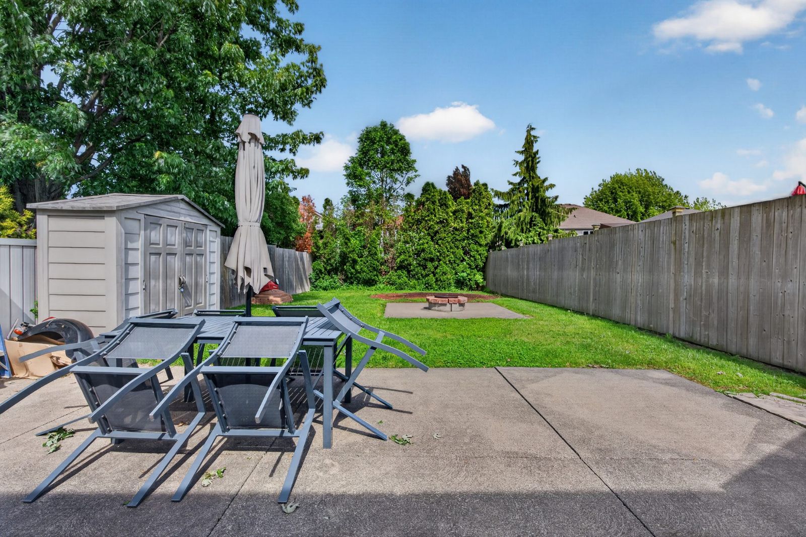 Concrete patio with outdoor furniture, storage shed, and fenced backyard
