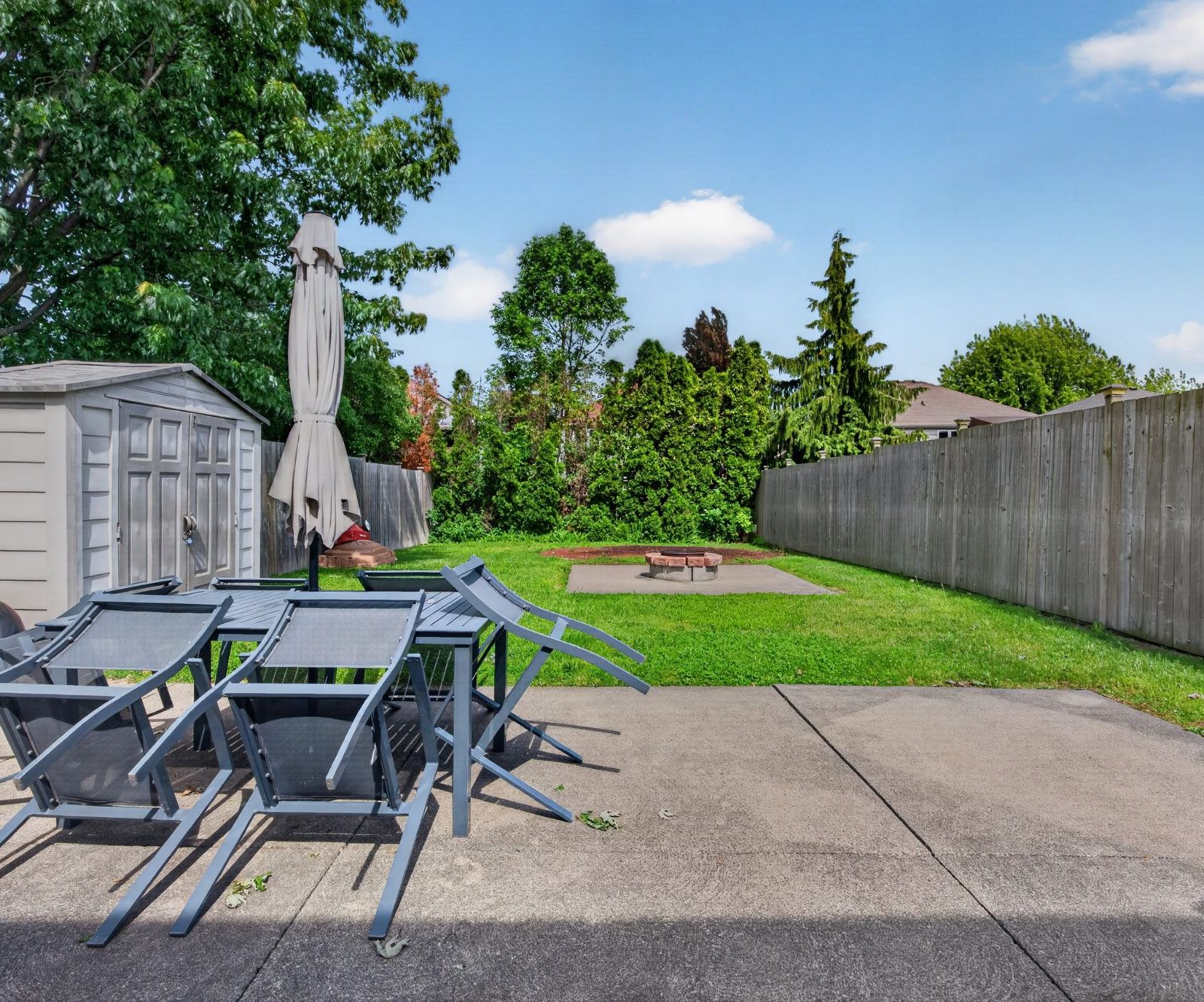 Concrete patio with outdoor furniture, storage shed, and fenced backyard
