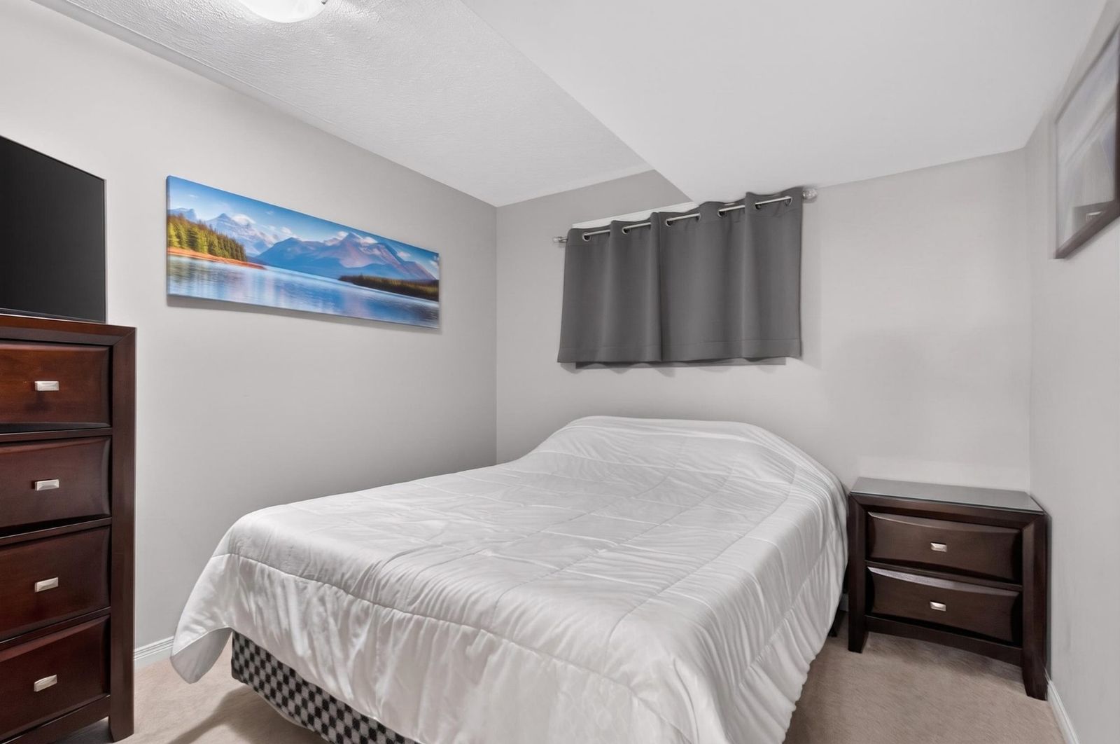 Lower level bedroom with dark wood furniture and grey curtains