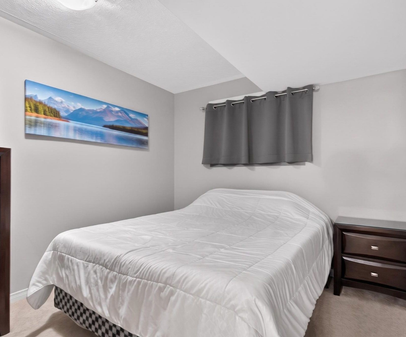 Lower level bedroom with dark wood furniture and grey curtains