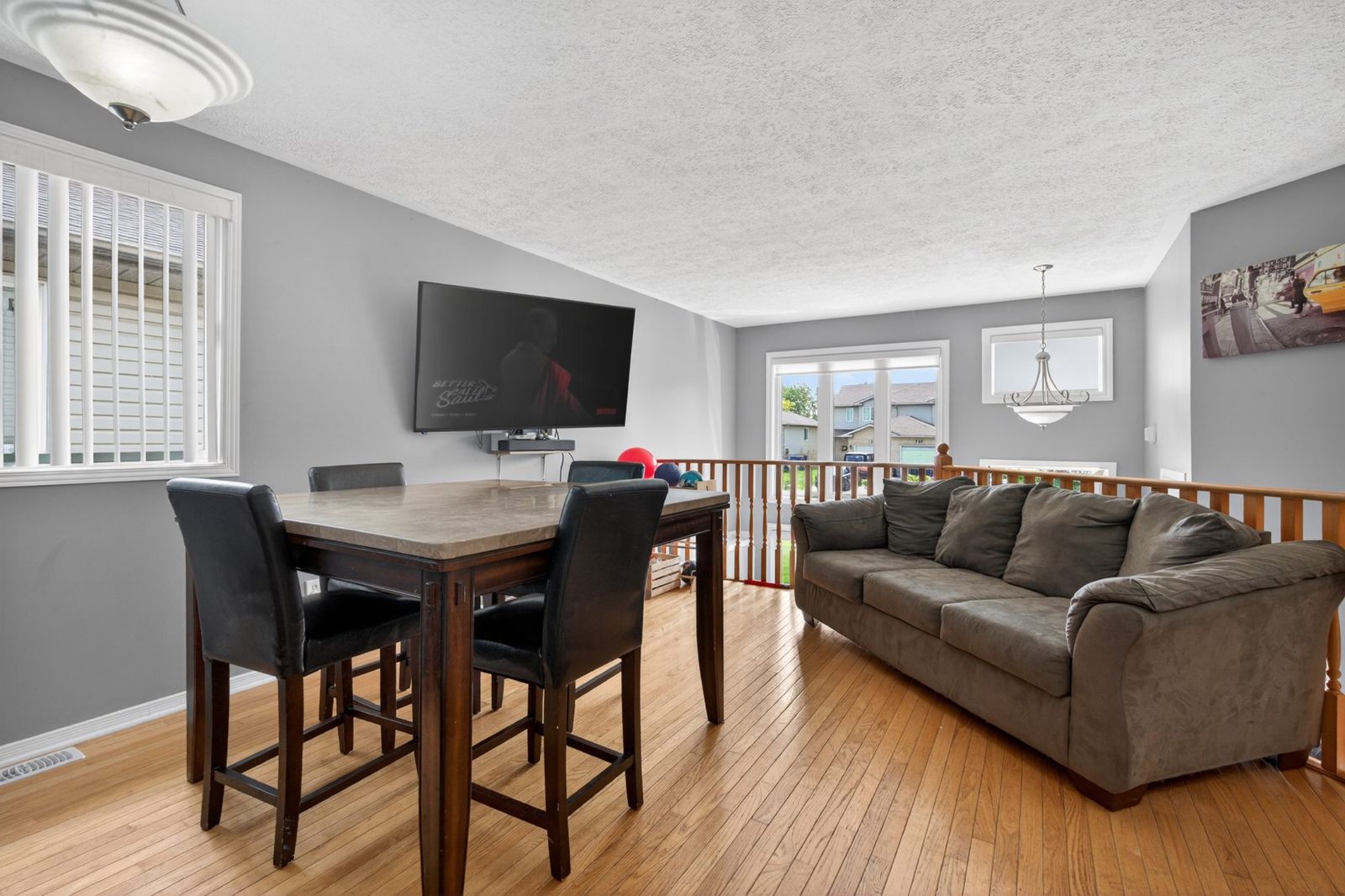 Living room with hardwood floors, large windows, and dining area
