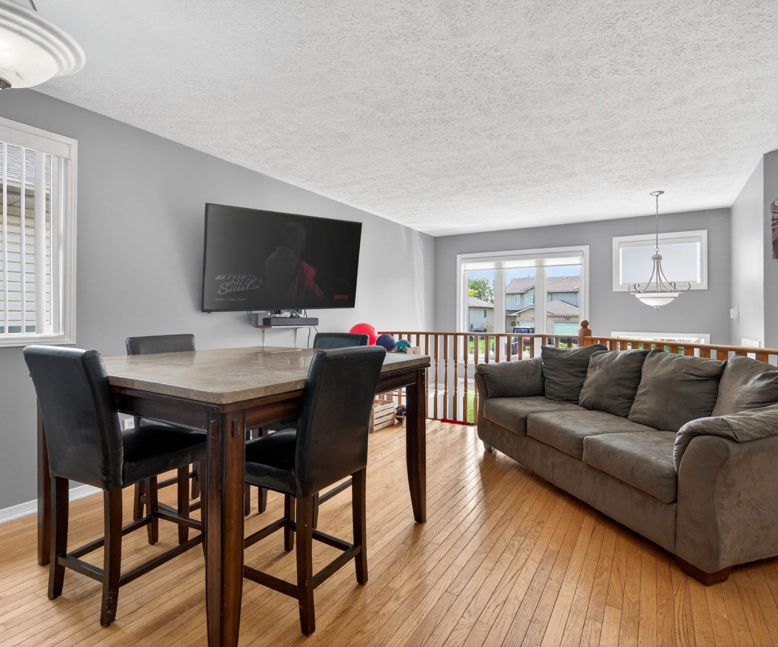 Living room with hardwood floors, large windows, and dining area