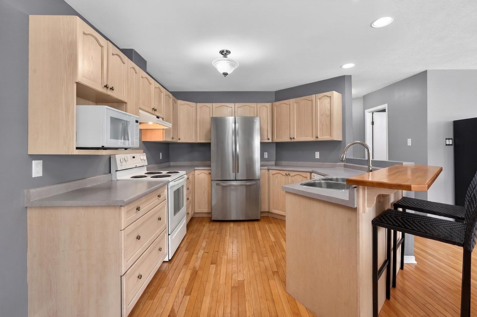 Kitchen with light maple cabinetry and stainless refrigerator