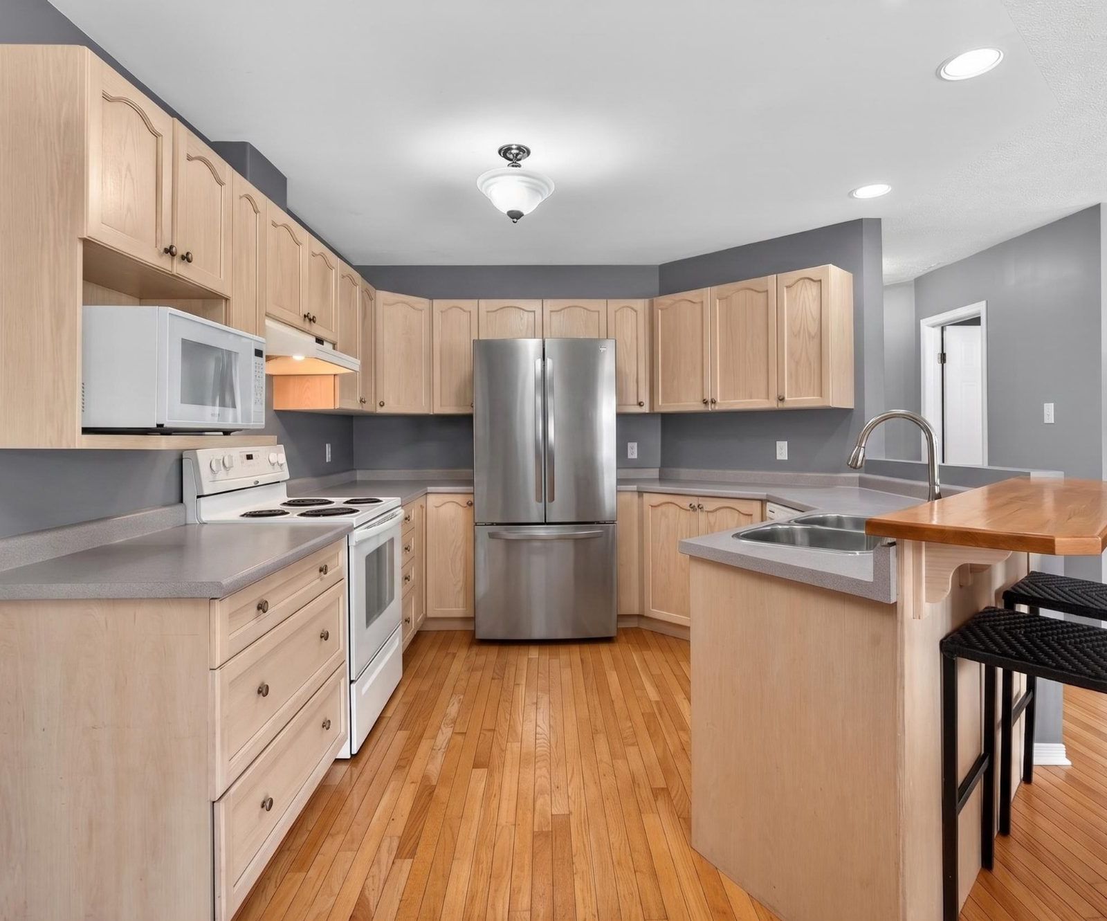 Kitchen with light maple cabinetry and stainless refrigerator