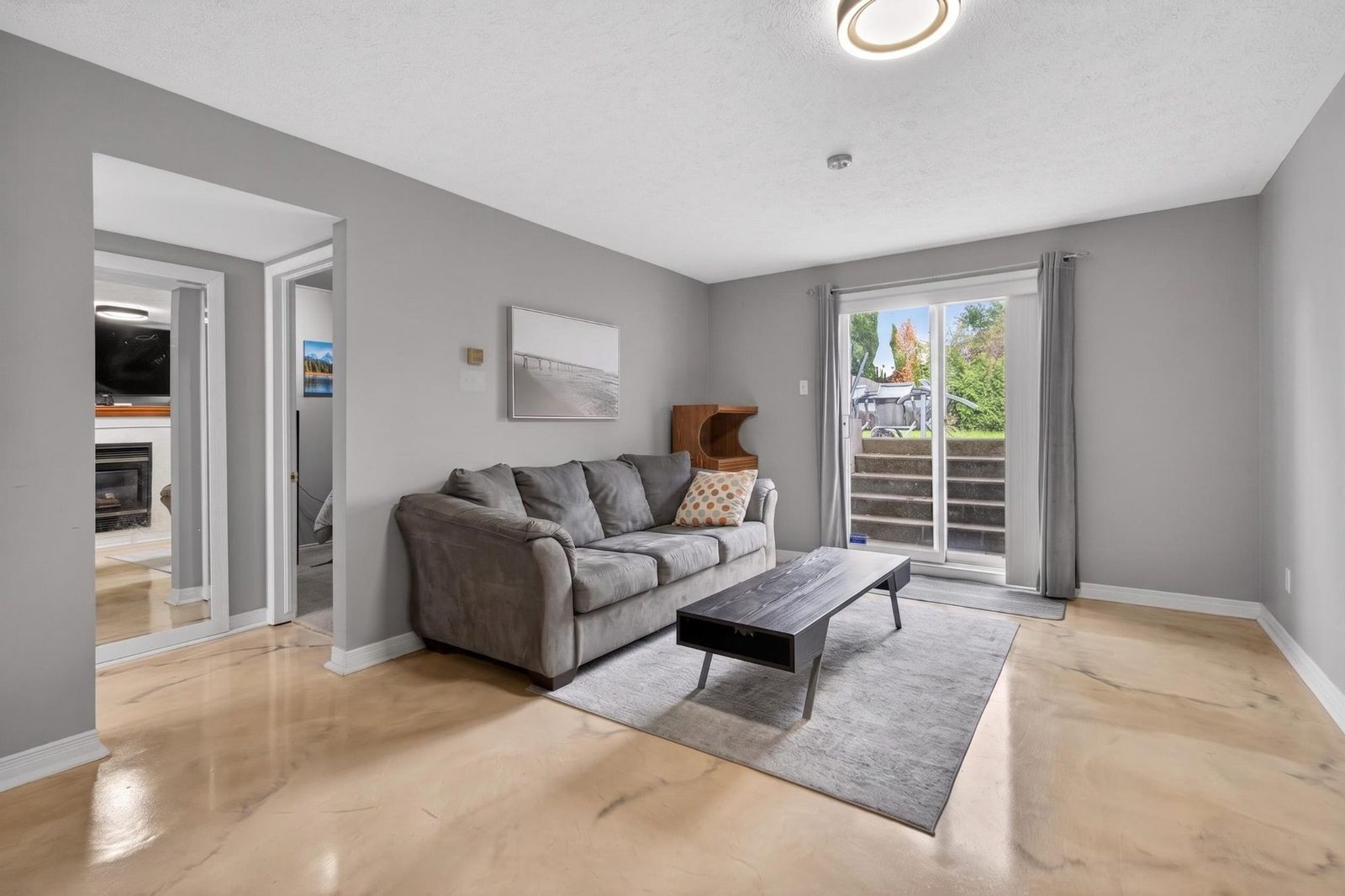 Lower level living room with grey couch and sliding door