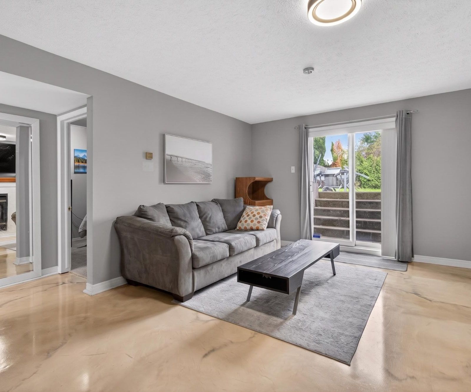 Lower level living room with grey couch and sliding door