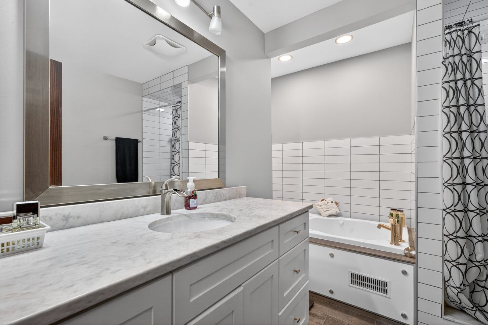 Bathroom - vanity with countertop, large mirror, bathtub with tile surround