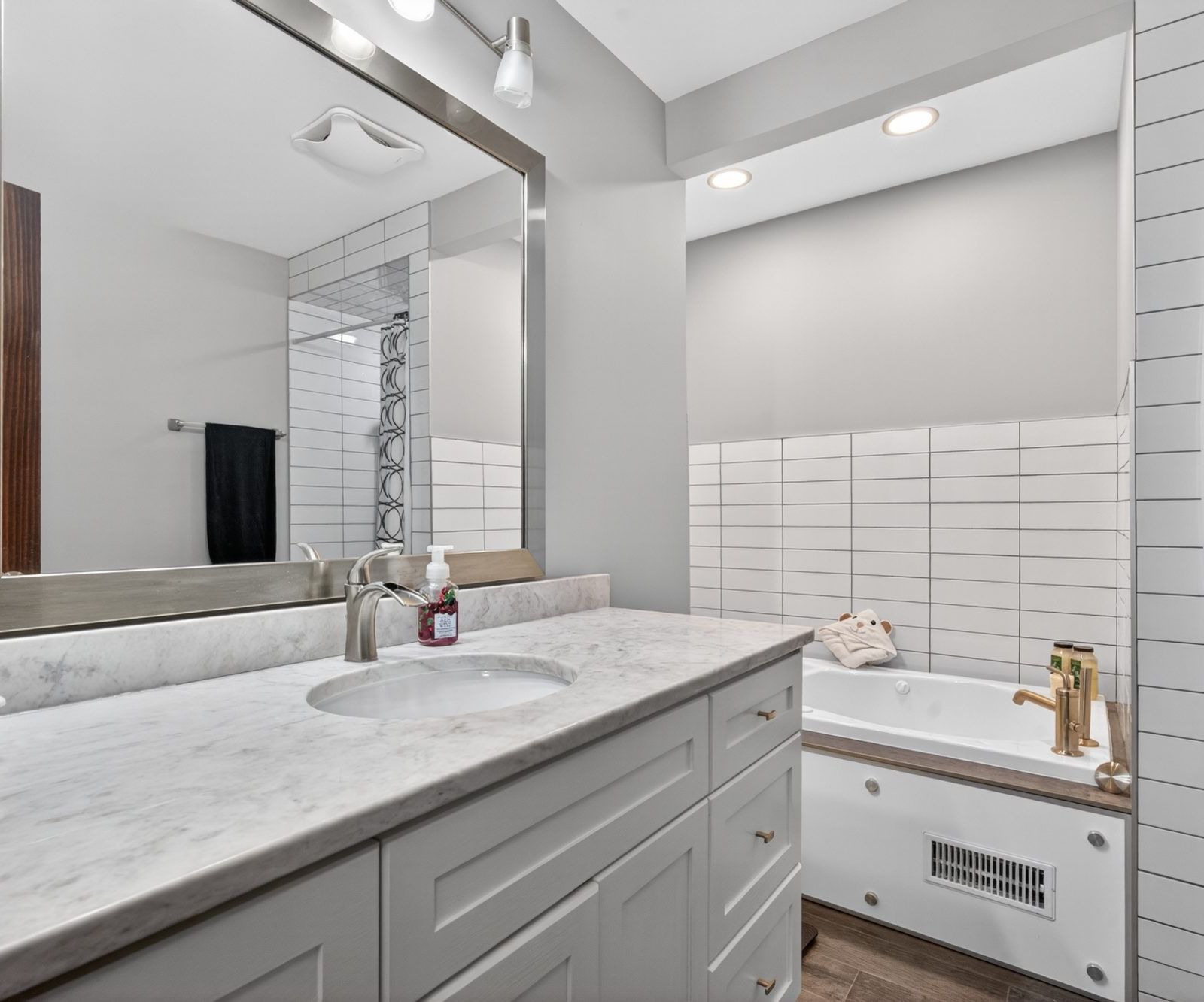 Bathroom - vanity with countertop, large mirror, bathtub with tile surround
