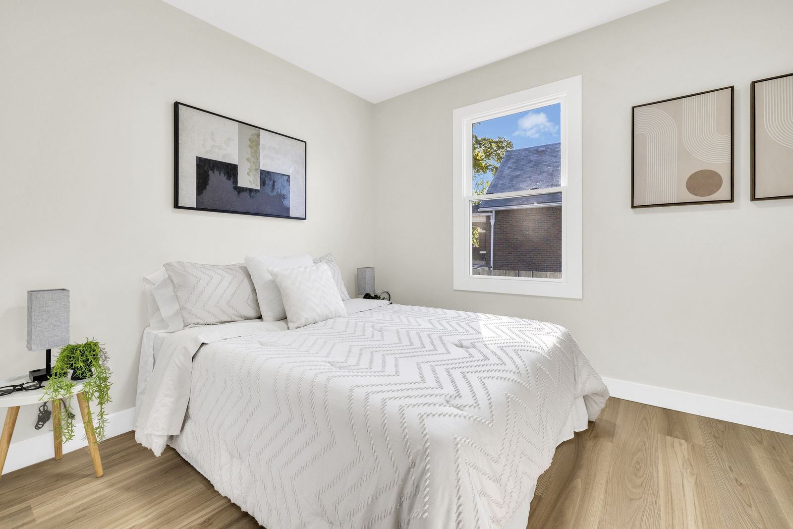 Bedroom with a bed, a window and framed pictures.