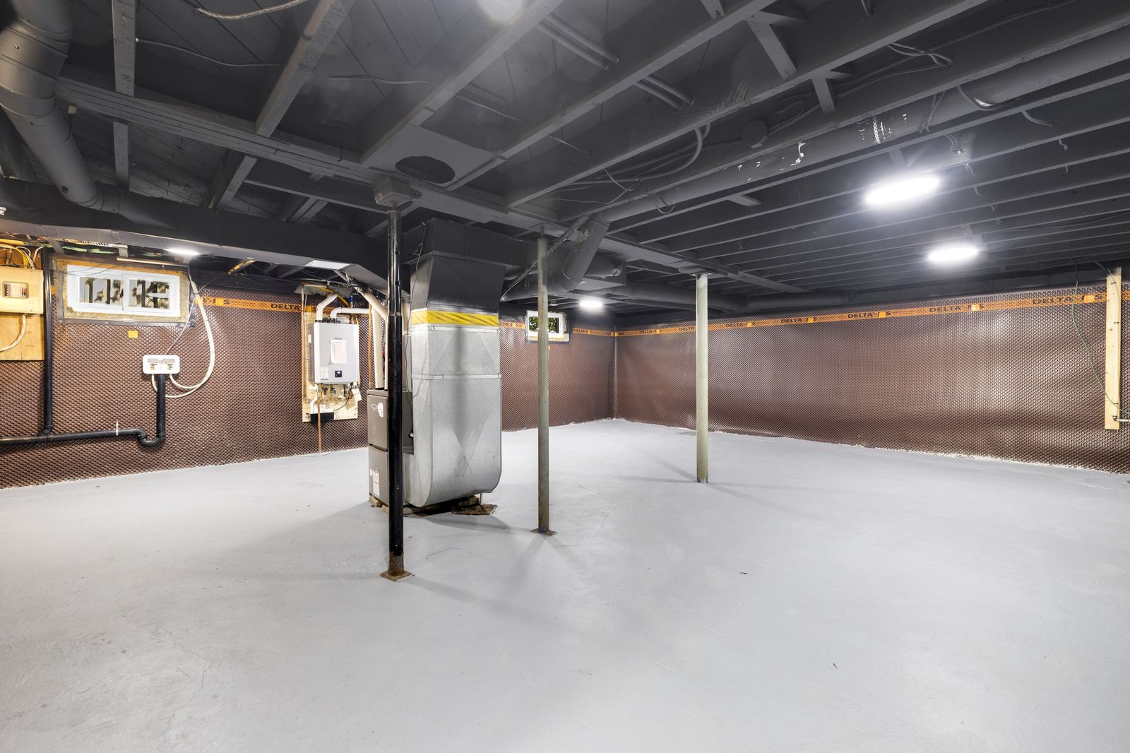 Unfinished basement with the electrical panel, the furnace and ductwork.