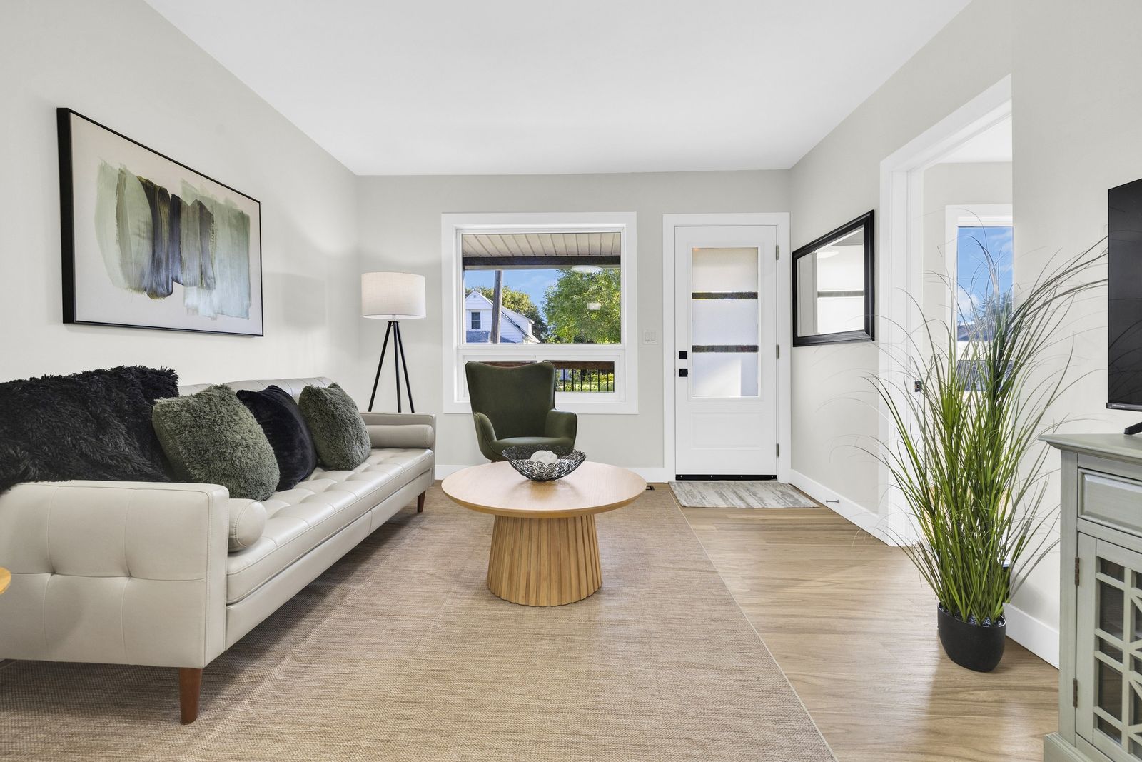 Living room with a sofa and coffee table, looking toward the front door and front window.