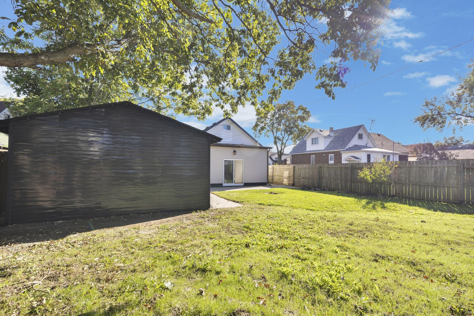 Backyard lawn with the detached garage on the left and the back of the house beyond.