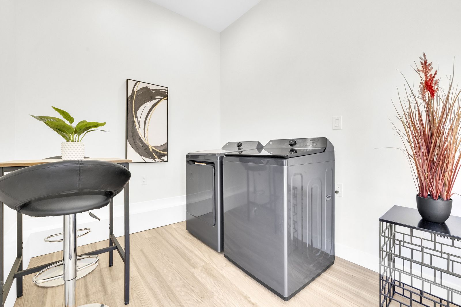 Washer and dryer beside a small table and stool.