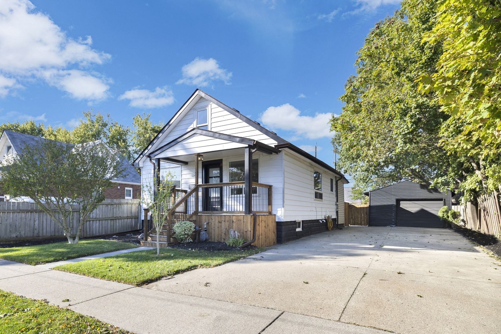 Front of the house with the covered porch, the concrete driveway and the detached garage at the back.